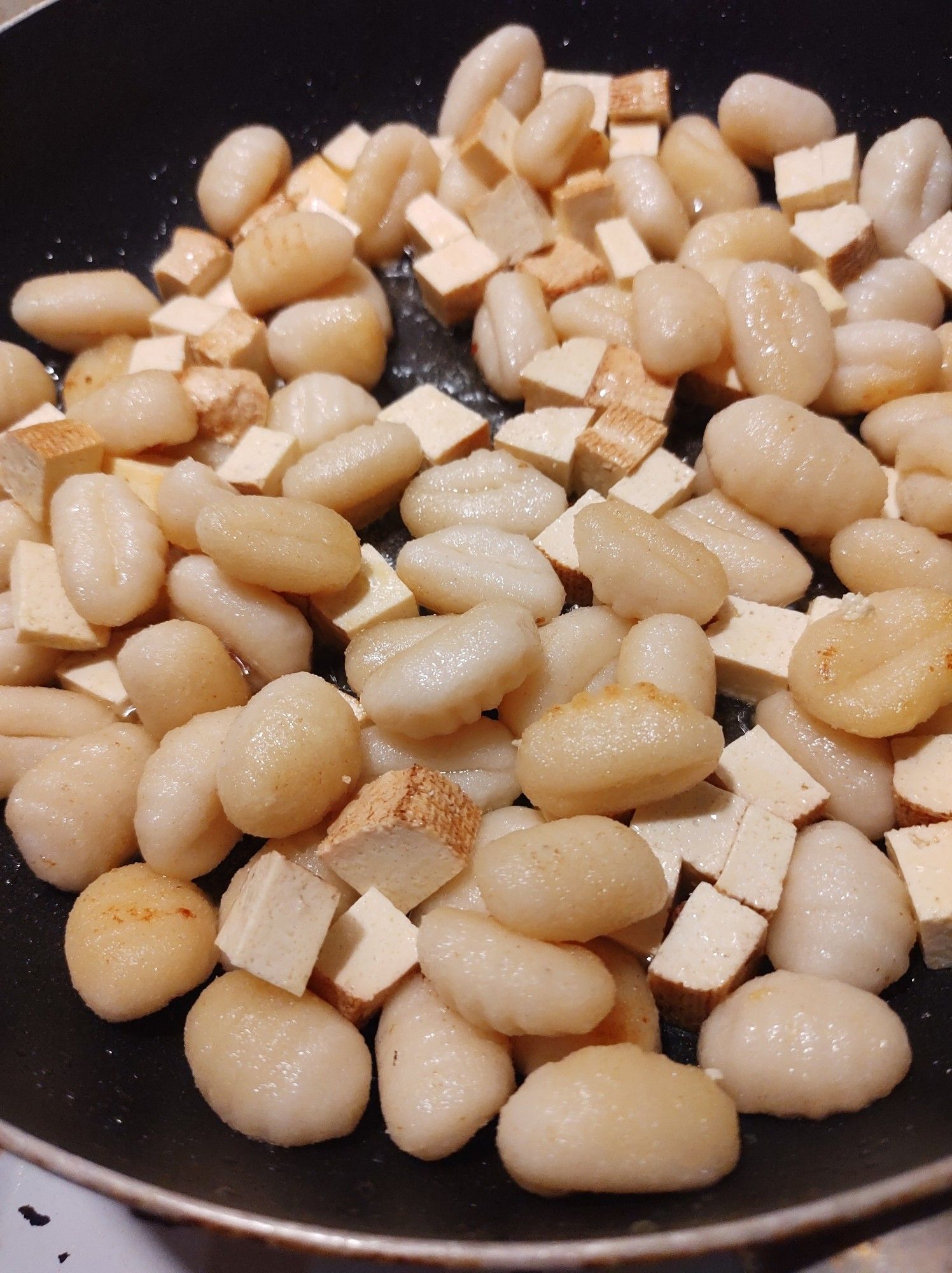 Veganes Rosenkohlgericht - Gnocchi mit gewürfeltem Räuchertofu in Butter und Öl braten in hoher Pfanne vor.