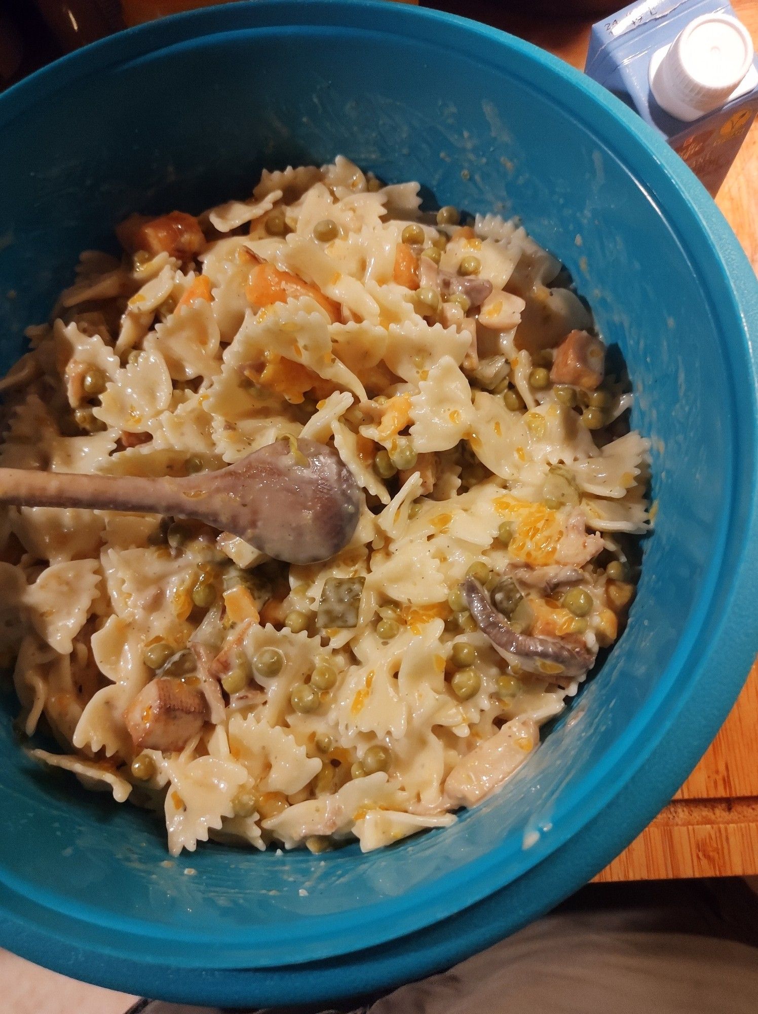 Veganer Nudelsalat, frisch zubereitet in großer Tupperschüssel, Holzlöffel zum Umrühren liegt obenauf 

500g Farfalle kochen, abkühlen lassen

Dressing:
1 Glas vegane Mayo (250 ml) halb in die Schüssel, zum Rest im Glas Teelöffel Senf und Salz und mit etwas Gurkenwasser auffüllen, schütteln und zur Mayo gießen, noch nach Bedarf mit Pfeffer und Petersilie würzen, 2 Zehen Knoblauch reinpressen.

Bonus: Mandarinen oder in Würfel geschnittene Pfirsiche aus der Dose dazu.

Räuchertofu mit Zwiebelwürfeln anbraten und nachdem die Farfalle schon reingemengt sind, mit hineinrühren.

Das ganze halbe Stunde im Kühlschrank kaltstellen.