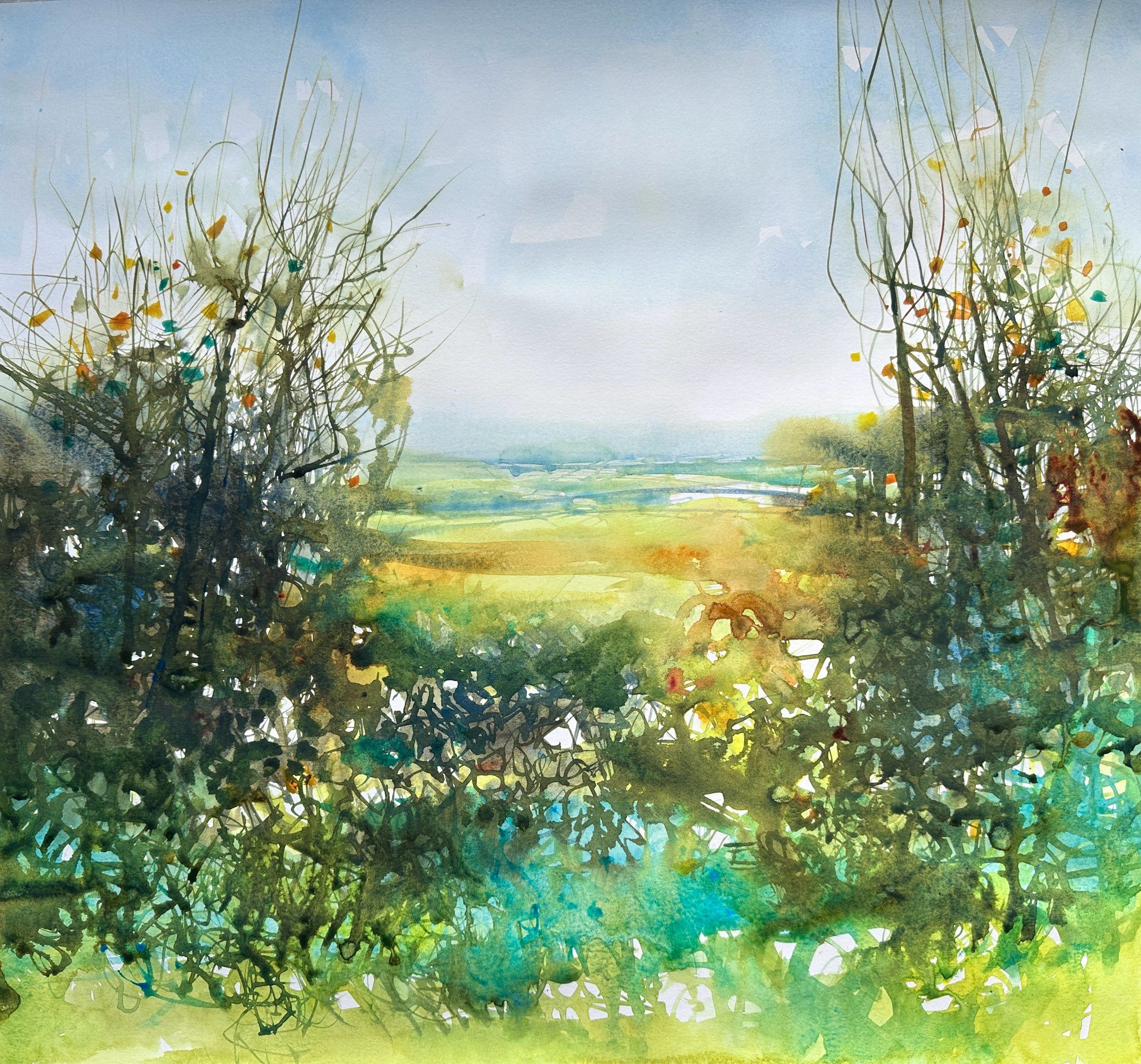 Autumn hedgerow with blues and greens, overgrown on either side with longer, almost bare branches. The opening in the middle of the hedge reveals a view of distant green fields, with hints of orange and yellow/green, under a pale blue sky