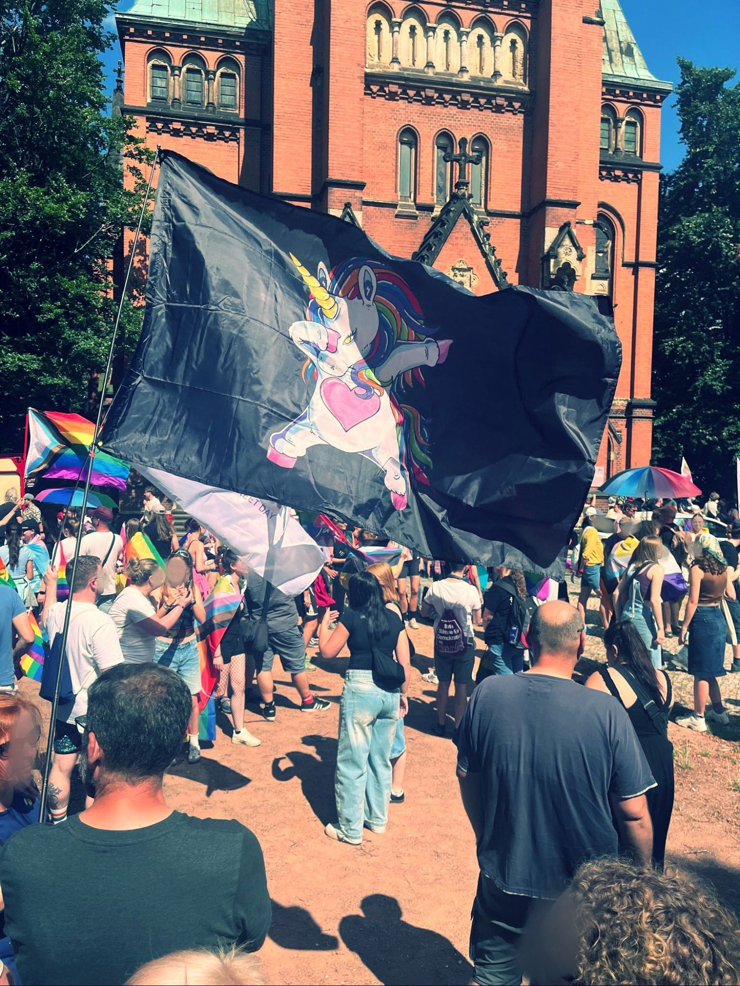 Der Markplatz in Bautzen voller Menschen mit Regenbogenflaggen. Eine große Flagge mit einem Einhorn ist auf der Mitte des Bildes zu sehen.