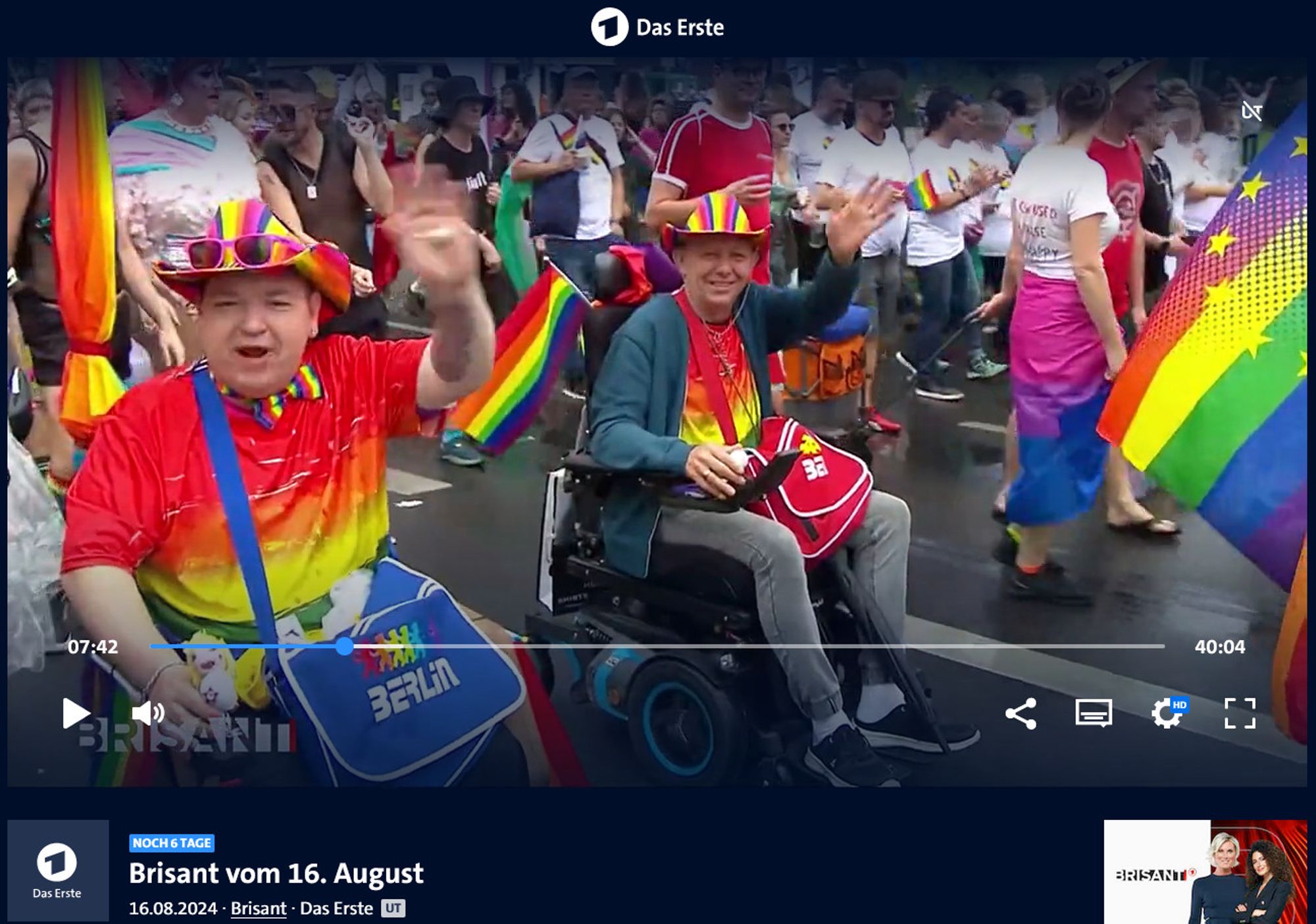 Screenshot von der ARD Mediathek, Brisant vom 16. August: Im Bild zu sehen, Menschen, mit vielen Regenbogenflaggen und Accessoirs, die gut gelaunt in Berlin den CSD feiern