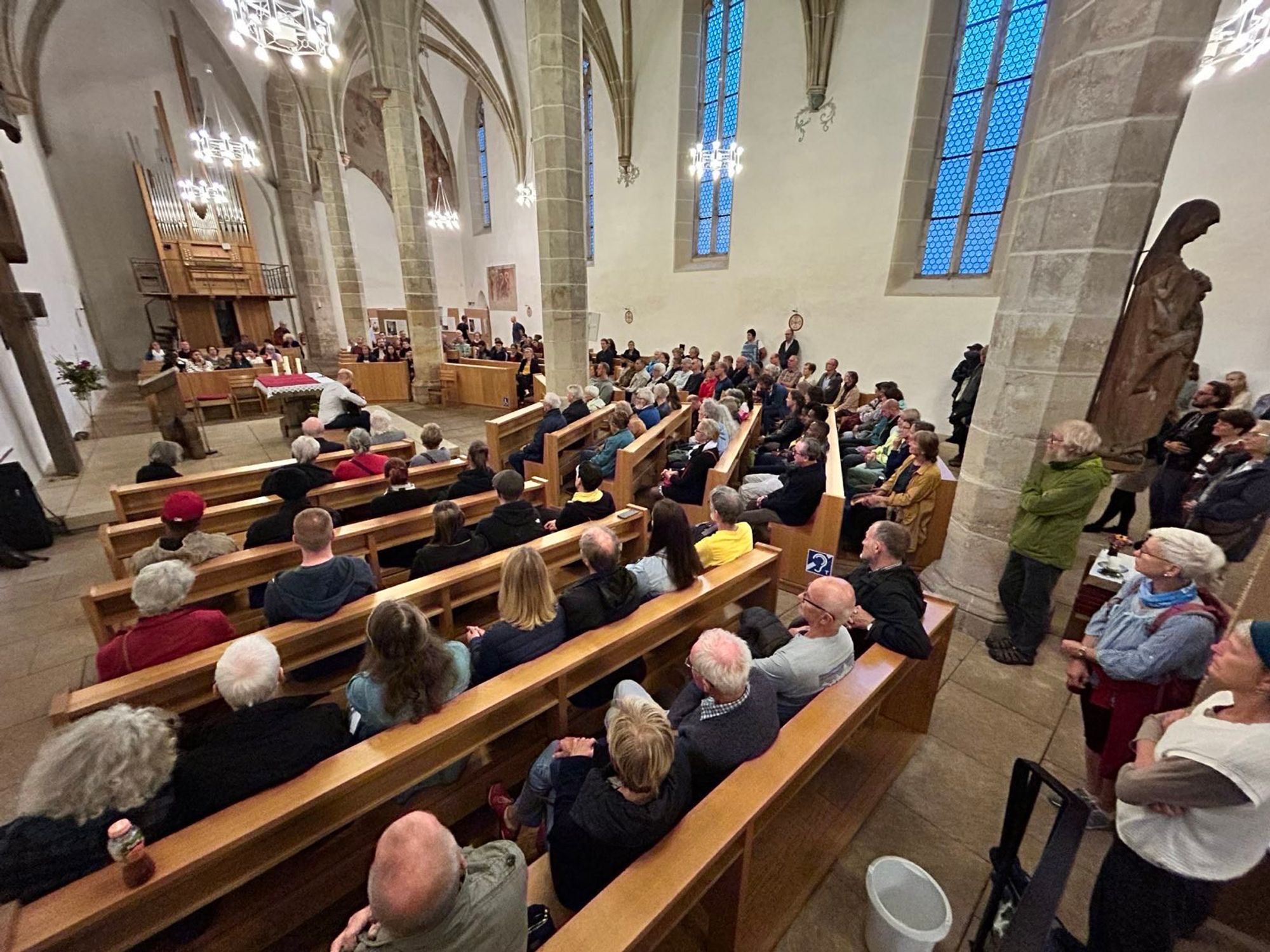 Viele Mensen sitzen auf Bänken und stehen in den Rängen einer Kirche in Pirna.