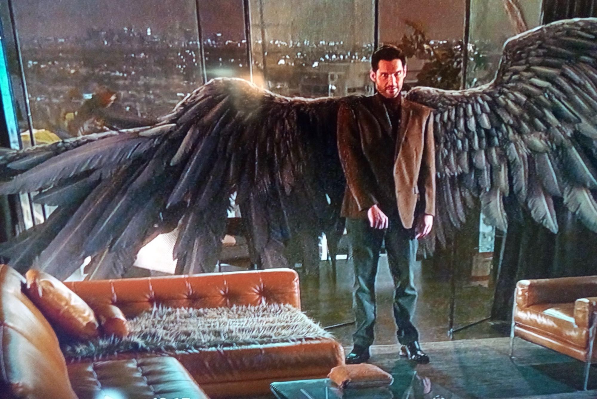 A screenshot of Michael from Netflix’s Lucifer show. His wings are spread, showing the right one’s wonky shape and ragged feathers.