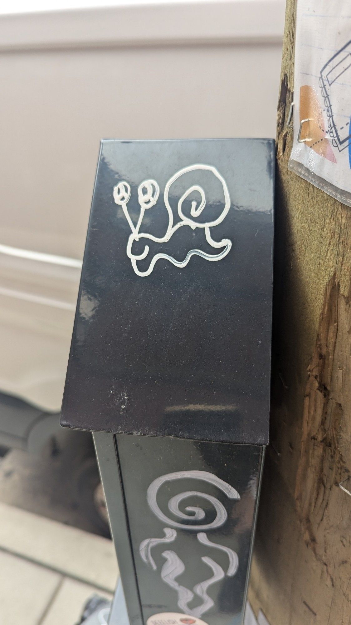 white graffiti snail on black utility box