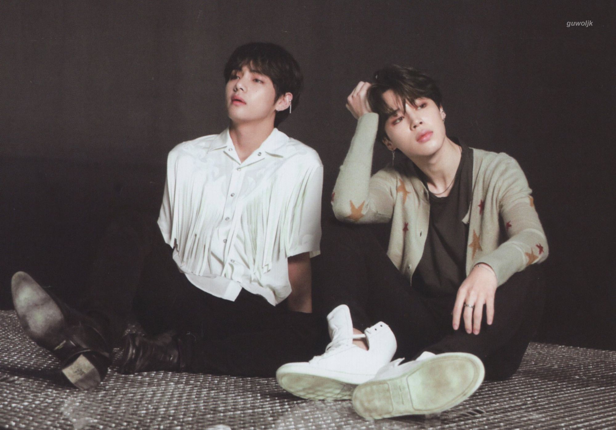 Taehyung and Jimin sitting on the floor; Tae is in black and white, Jimin in black with a gray star sweater on it.  Both frankly look tired as hell. Long shoot day?