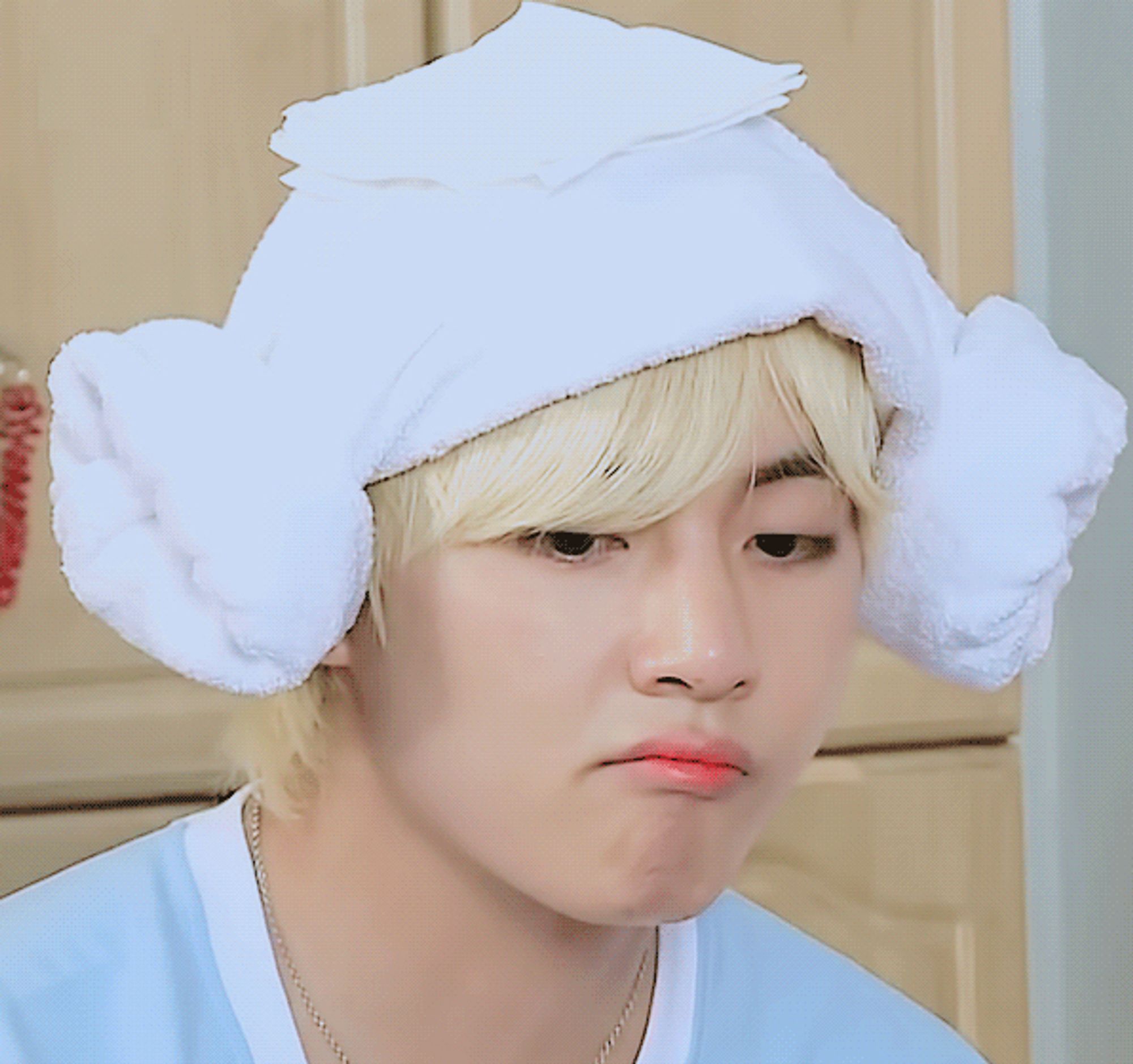 Taehyung with blond hair, towel over his head, napkin on top of towel which hides the egg he had to smash on his head.  He is POUTING cuz Yoongi won (much to his delight). Tae's shirt is white and light blue.