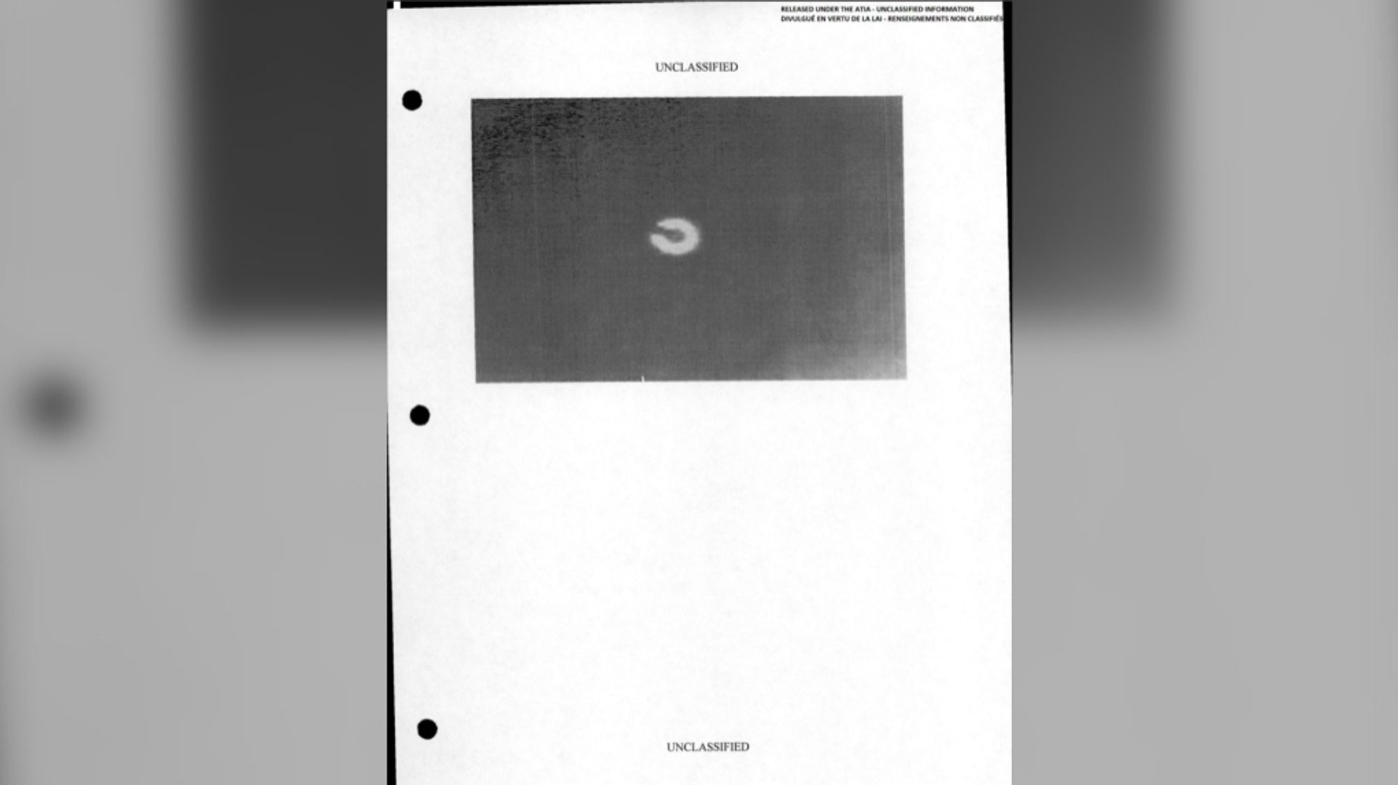 semicircle shaped disk labeled as unclassified on a white page (the photo is black and white and occupies the half of the page from the top). the page has two stapler holes