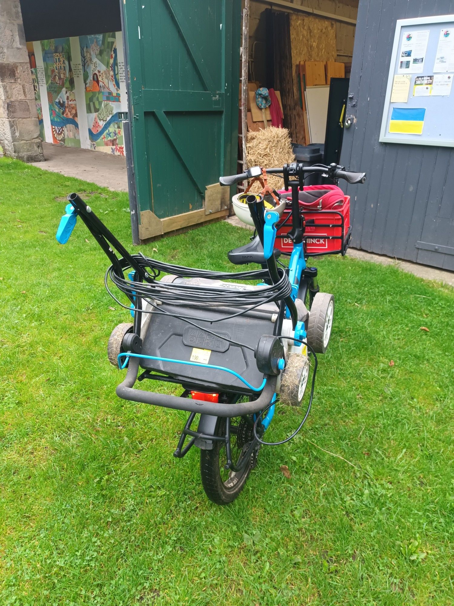 A rear view of aTern cargo bike loaded with a lawnmower