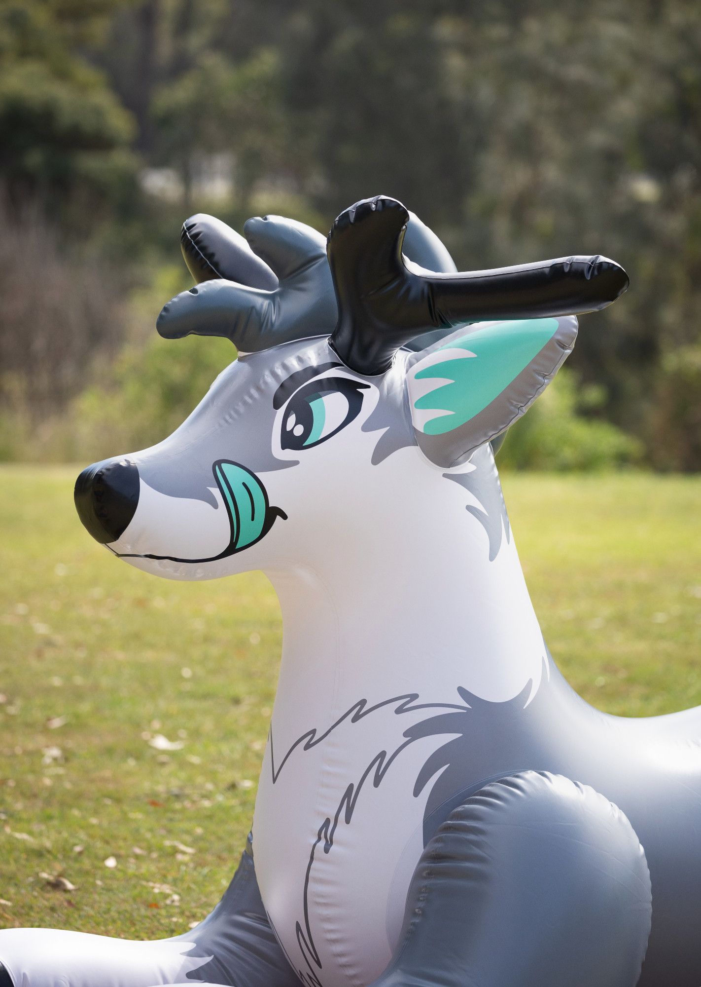 Portrait photo of the head and neck of a grey inflatable deer fursona, with printed tongue sticking out