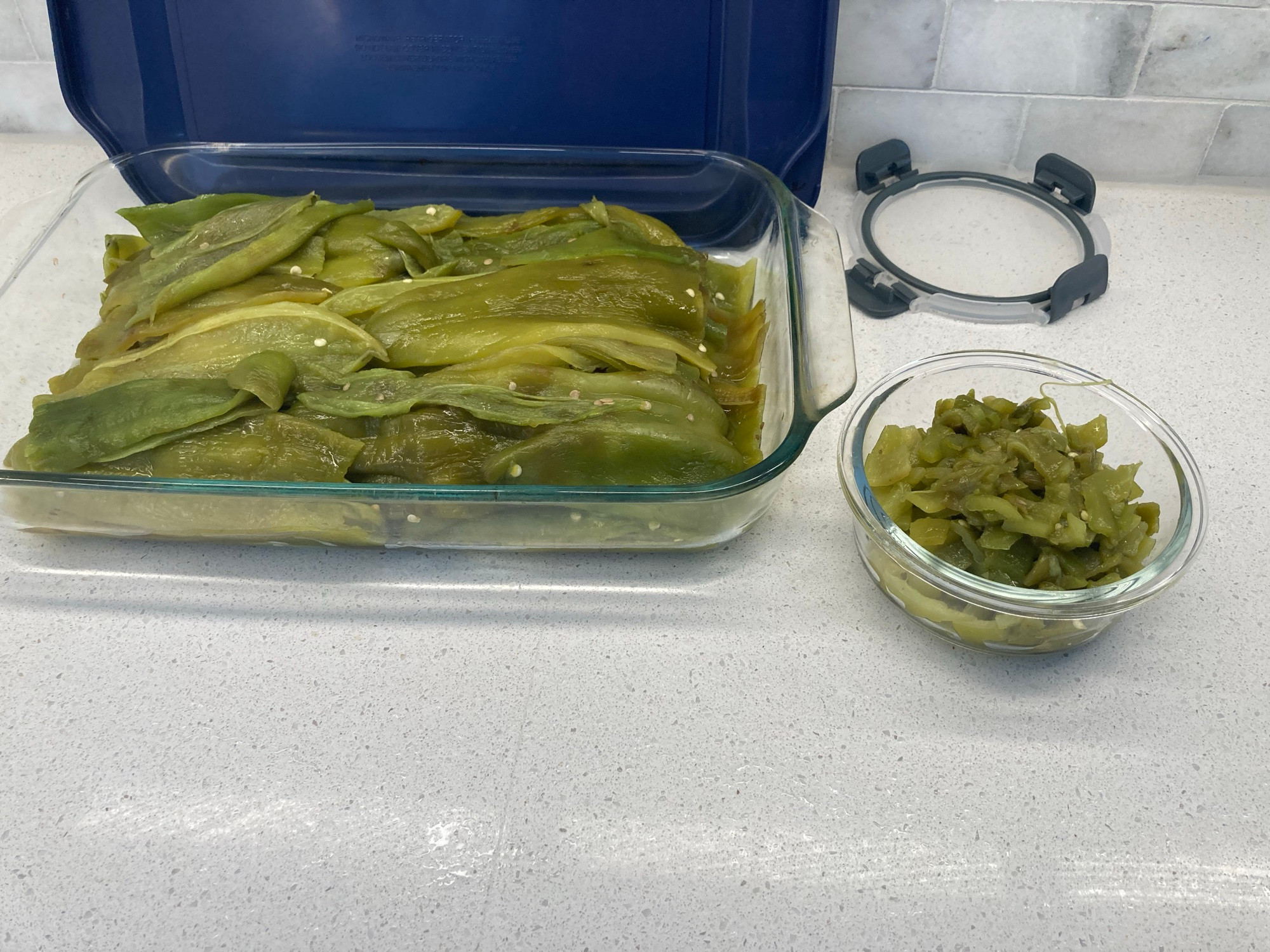 Pyrex dish filled with processed green chile halves and some diced chiles in a smaller glass bowl