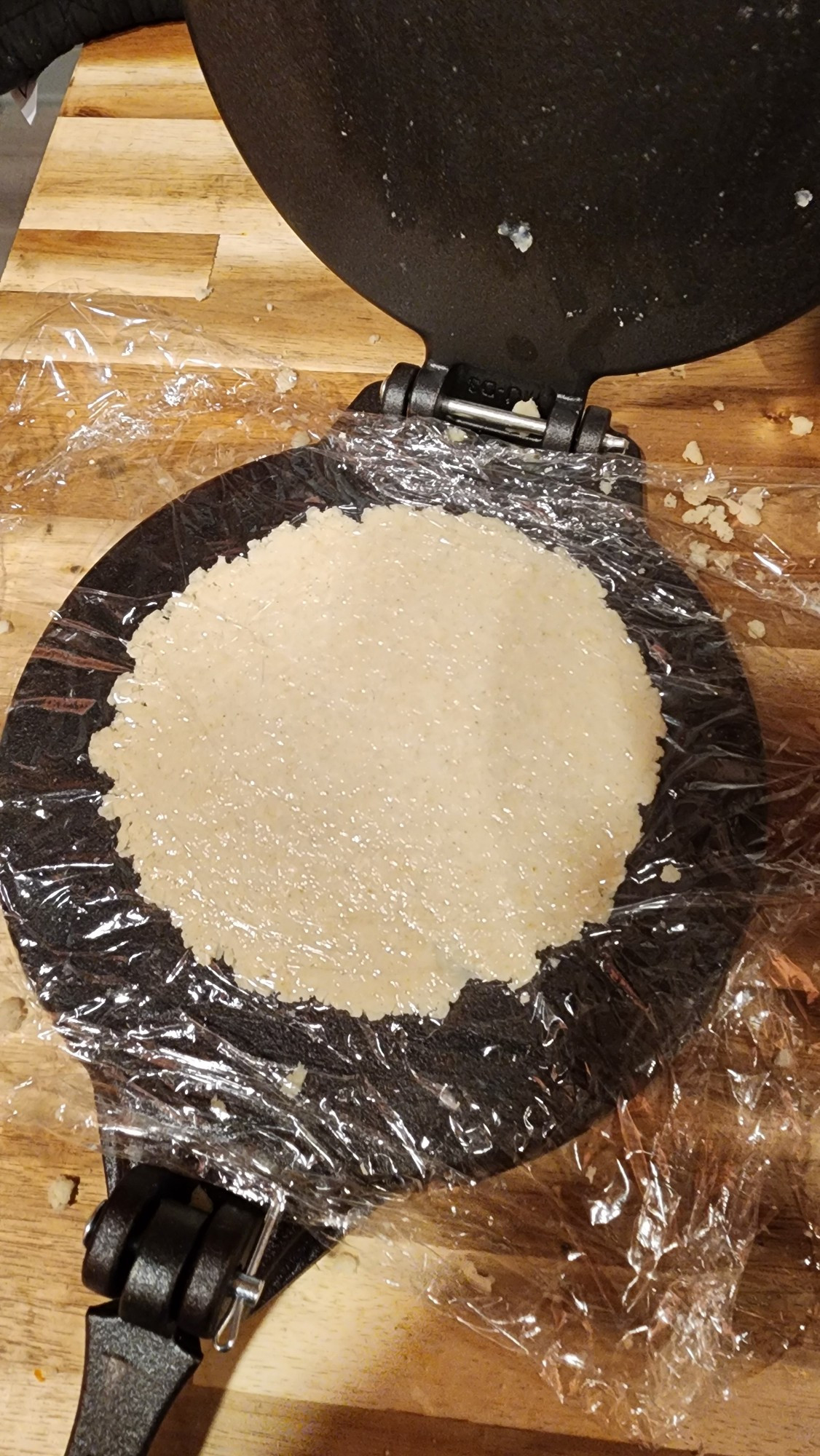 A reconstituted corn tortilla in a tortilla press