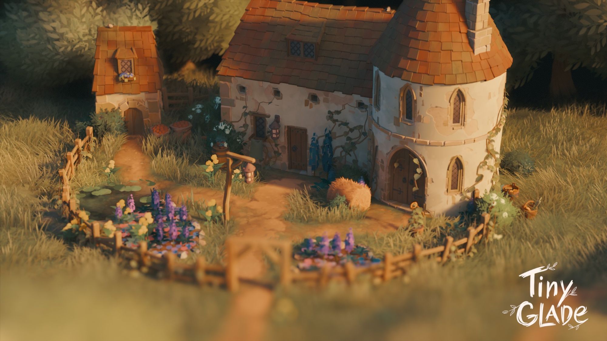 little medieval looking cottage with a square building attached the a round tower. There is also a small building to the side with a small door an tiny gabled window in the roof. The cottage is surrounded by flowers and a fence.