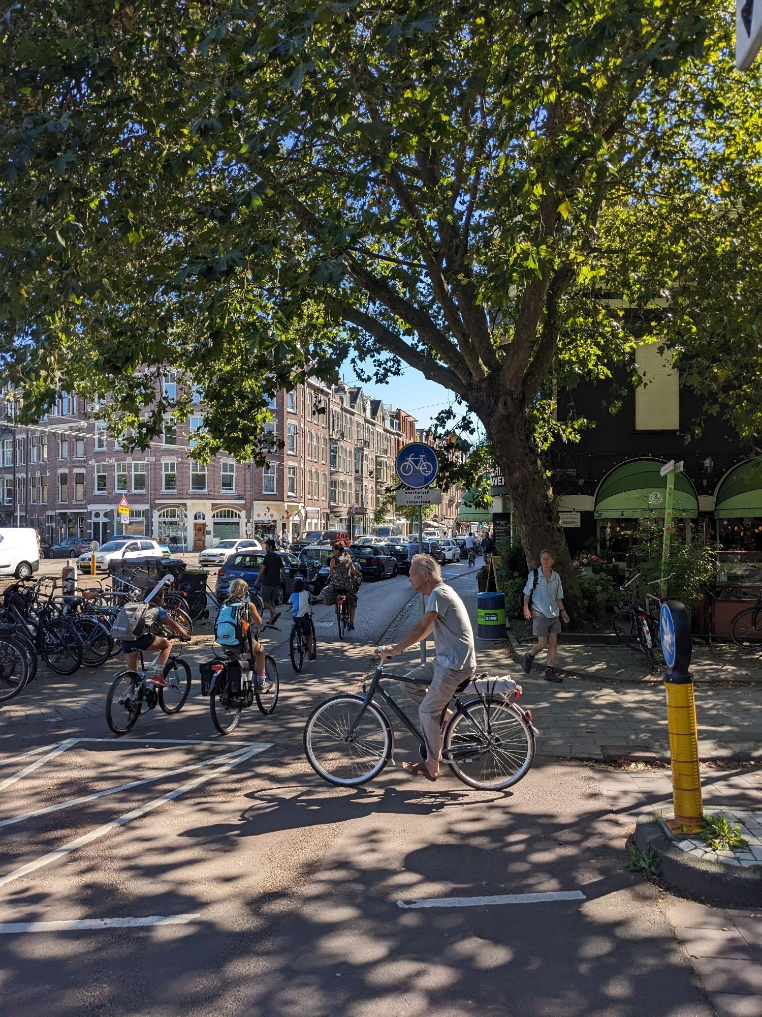 Ein älterer Herr auf einem Fahrrad und Kinder auf Fahrrädern in Amsterdam auf rot asphaltierter Radinfrastruktur