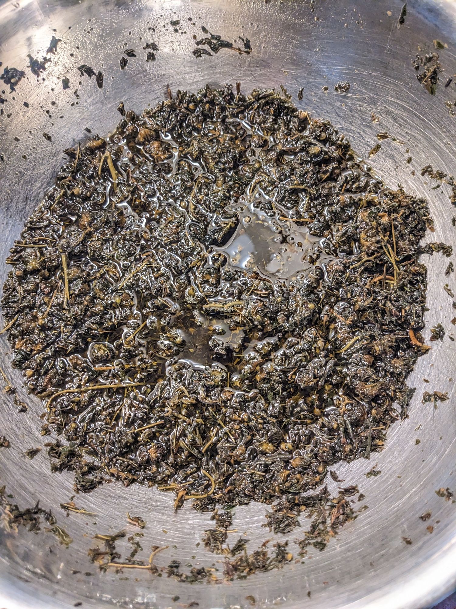 Weed and coconut oil in a silver mixing bowl during the infusion process