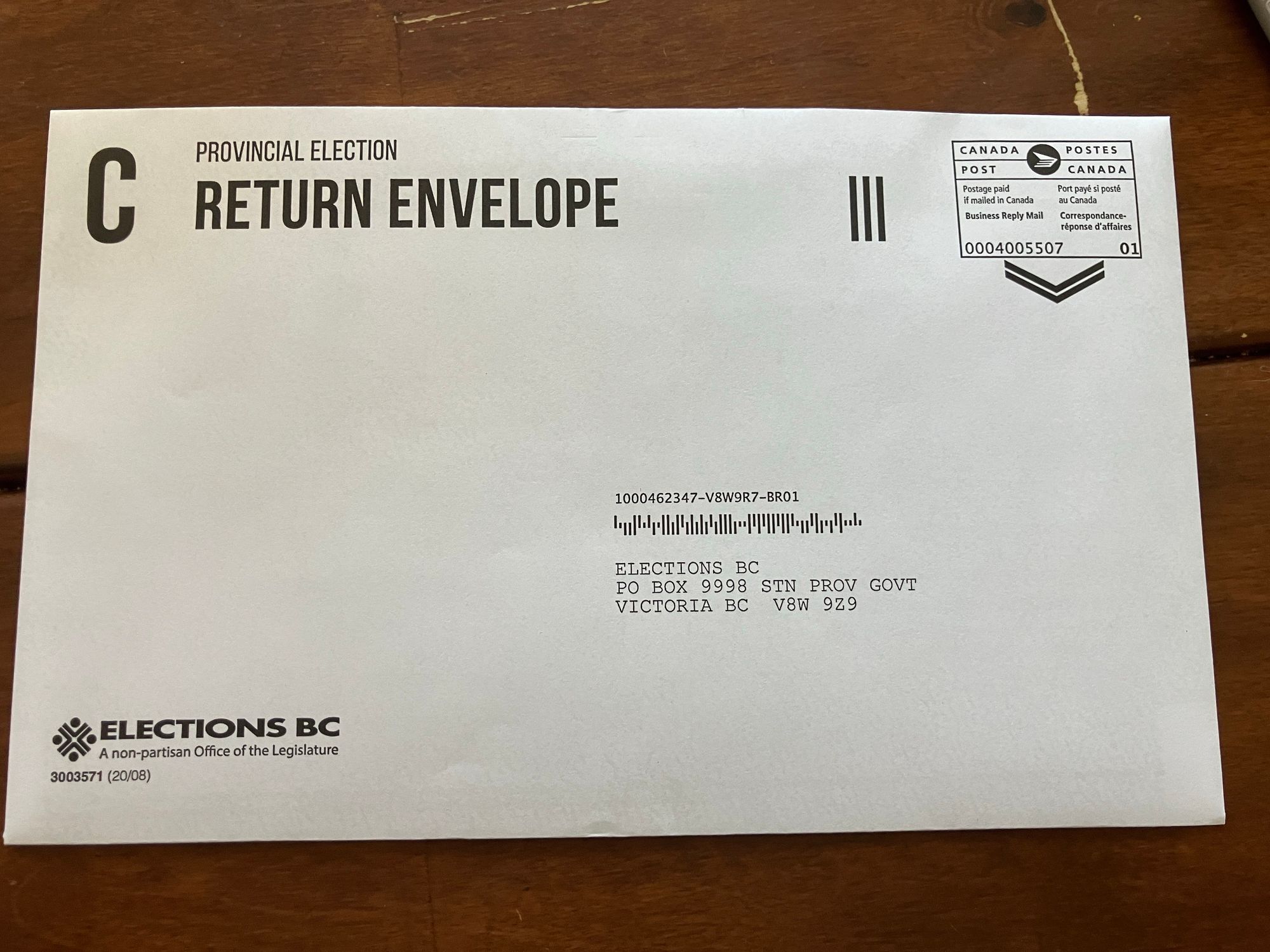 An envelope labeled "Provincial Election Return Envelope" from Elections BC. The envelope includes a postal label indicating it is for business reply mail, and it lists the address for Elections BC in Victoria, BC.