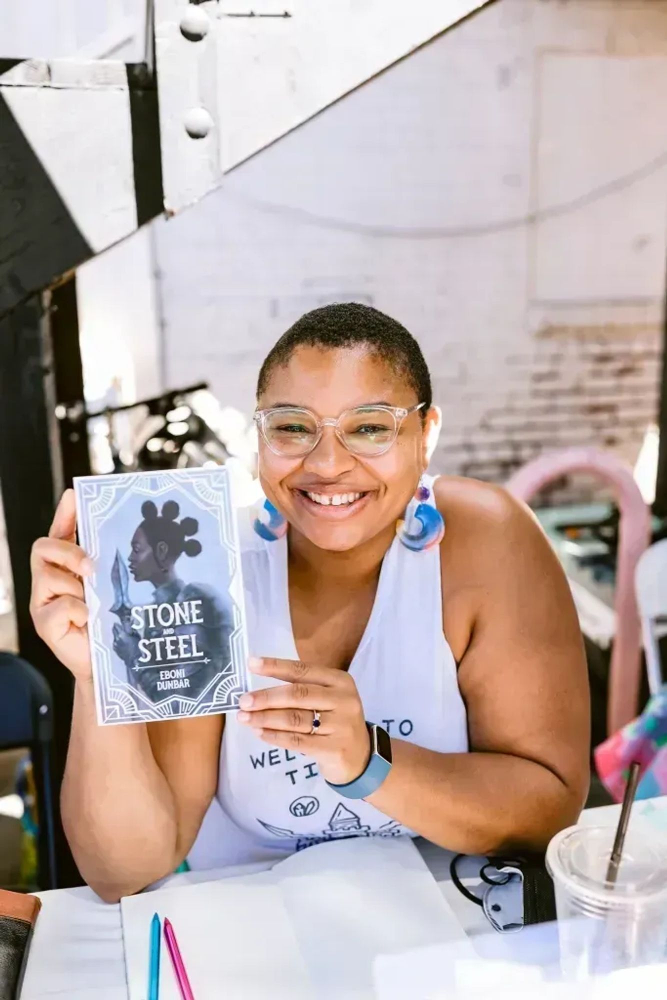 A photo of Eboni Dunbar, holding a book and smiling.