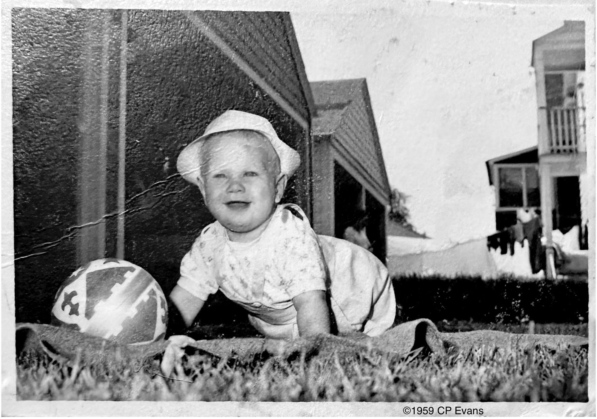 Little Chuck E., circa 1959, playing in the backyard of my grandma’s house. We lived with my grandparents while my dad finished college. Mom was already a teacher at the same college.

I am crawling on all fours, a huge smile on my face, and I am wearing a white sun hat. A plastic ball is in front of Kevin but I’m clearly responding to my dad’s encouragement to smile for Mommy or Grandmommy, or for whomever.