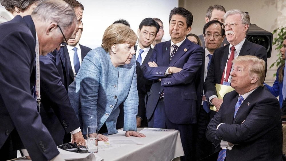 Foto vom G7-Gipfel: Angela Merkel redet mit aufgestützten Armen auf Donald Trump ein, um sie herum zahlreiche Regierungschefs.