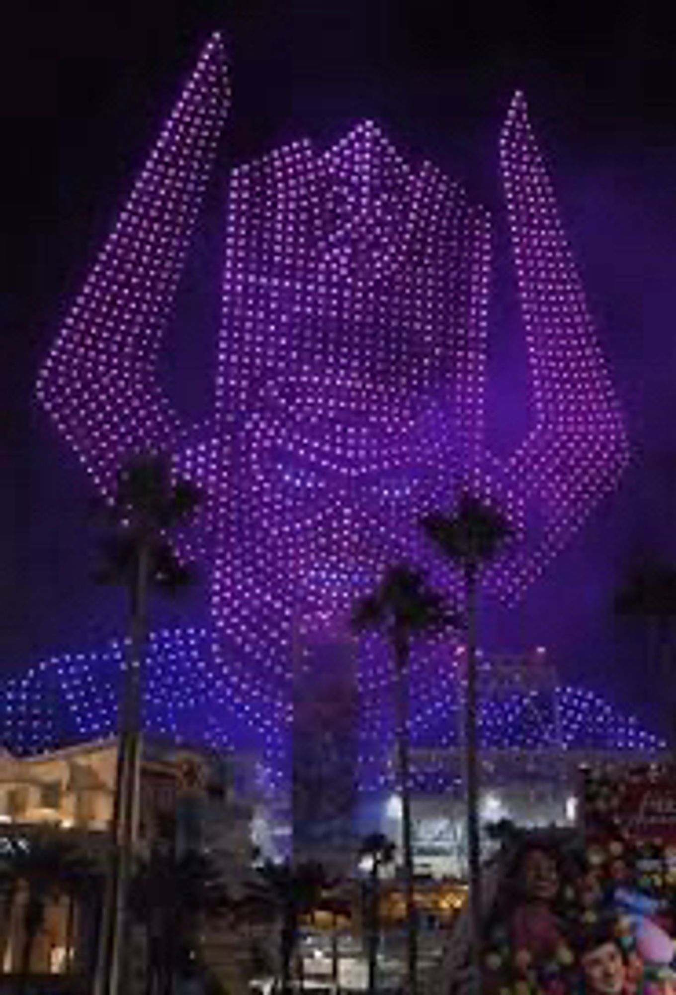 Drones forming the face and mask of Galactus, purple space god with hooked horns coming out of his helmet, looming over palm trees in the night sky of San Diego.