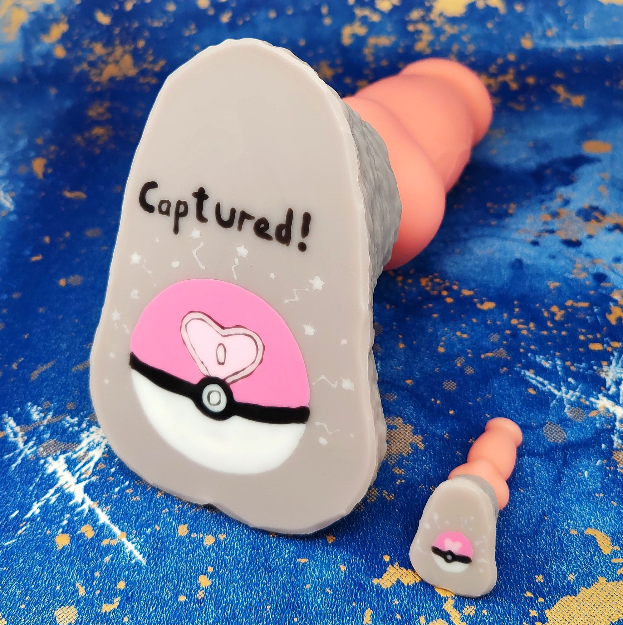 Daddy-Dog dildo with peach shaft, grey base and a Love Ball painted on the base with the text "Captured!".