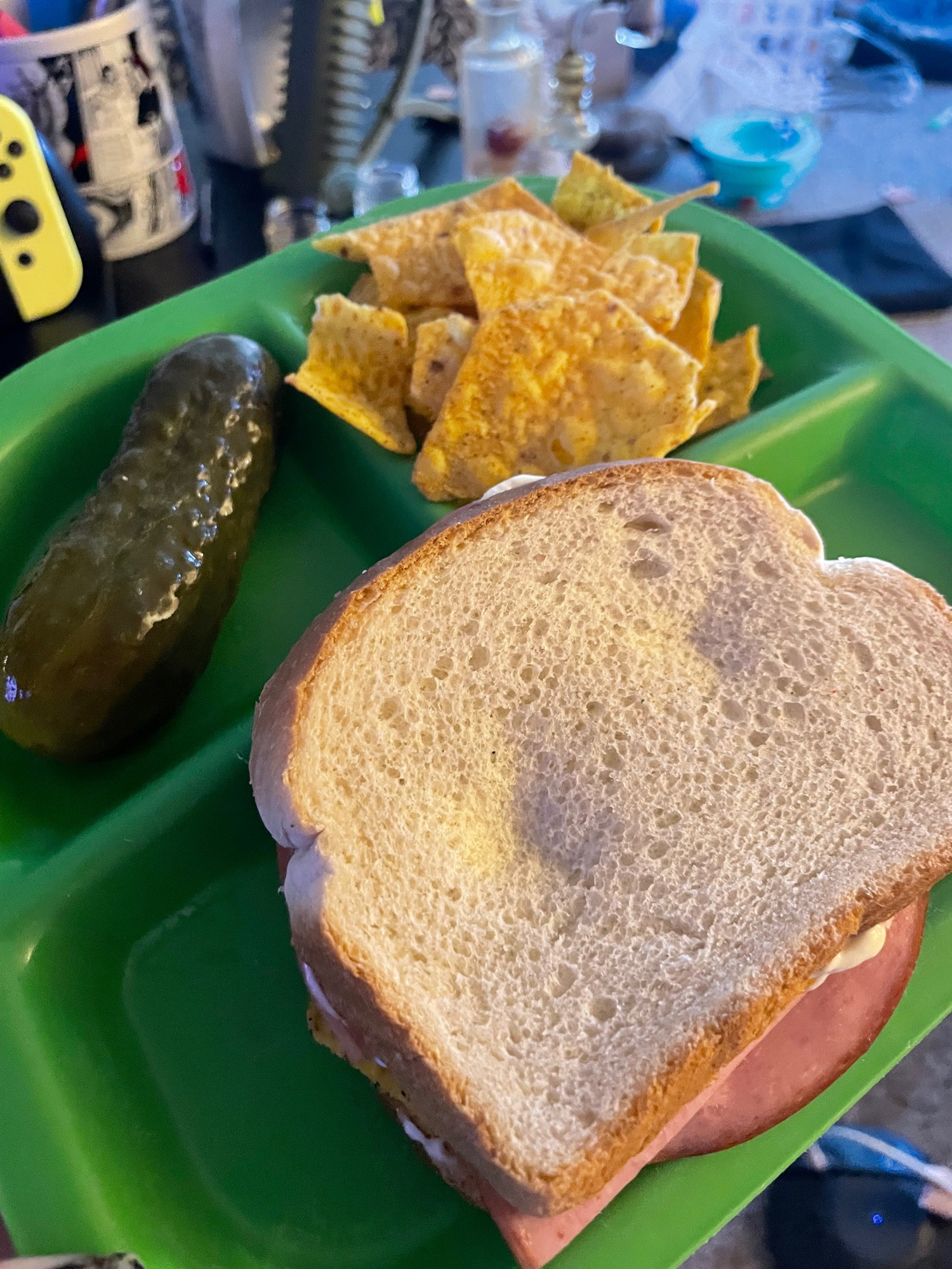 sectioned plate with a pickle, chips, and a sandwich corned beef and cheese with chips and mayo 