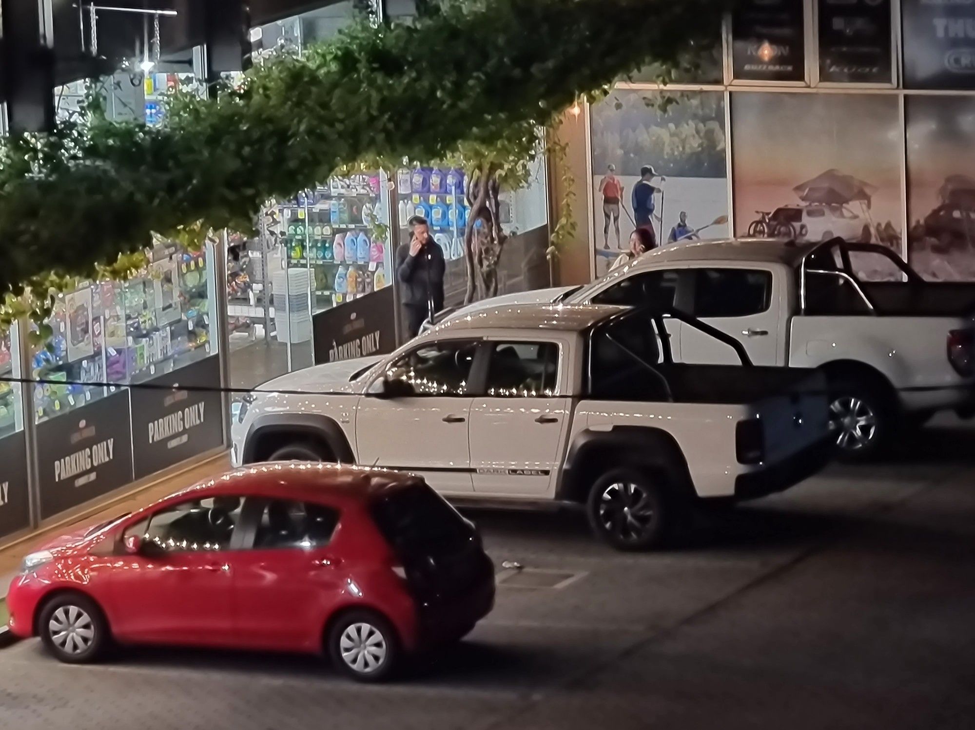 Cars parked outside a shop. The white truck on the far side is the culprit.