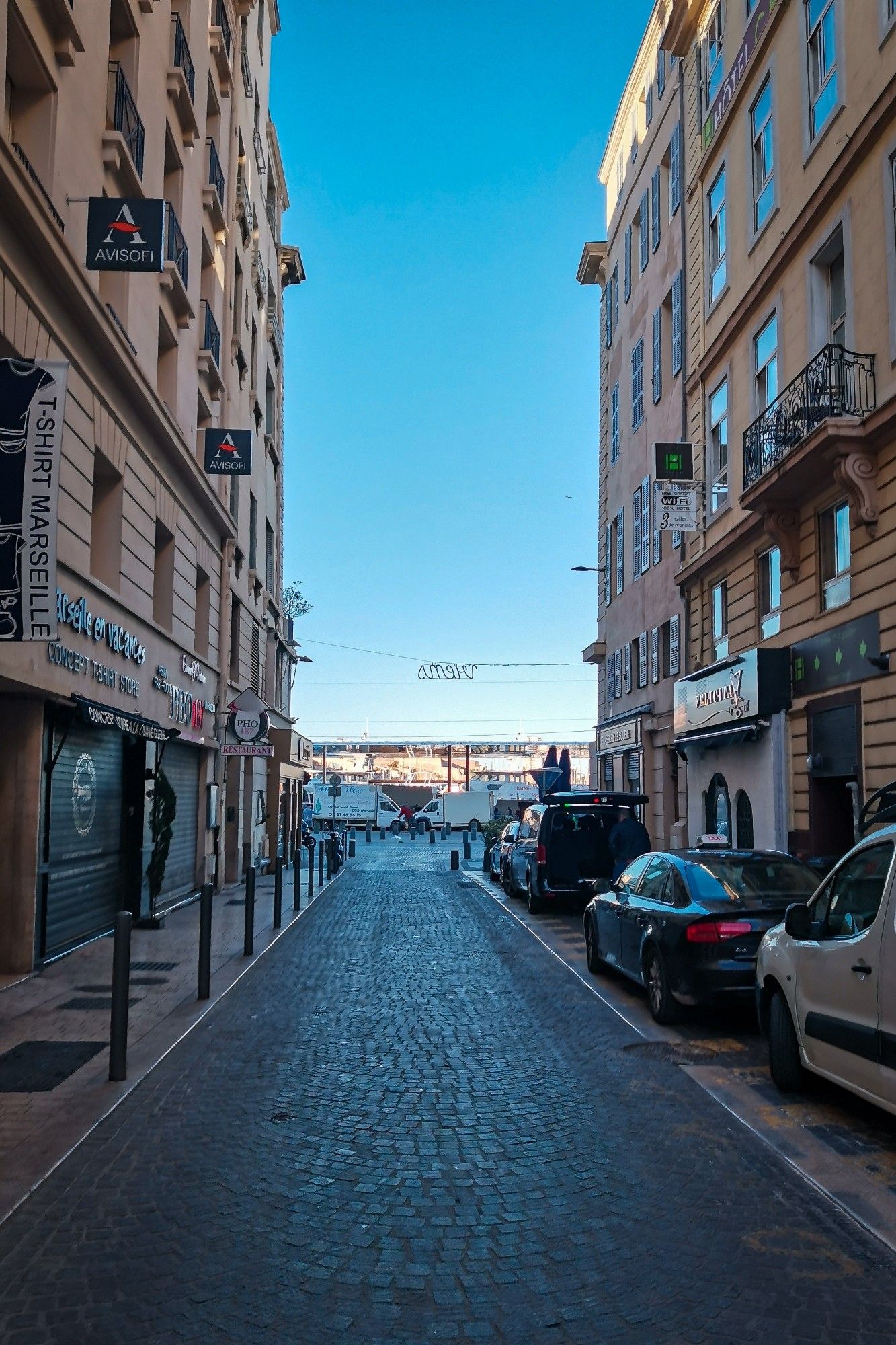 Une rue du Vieux-Port au dessus de laquelle est suspendue l'enseigne lumineuse "Viens".