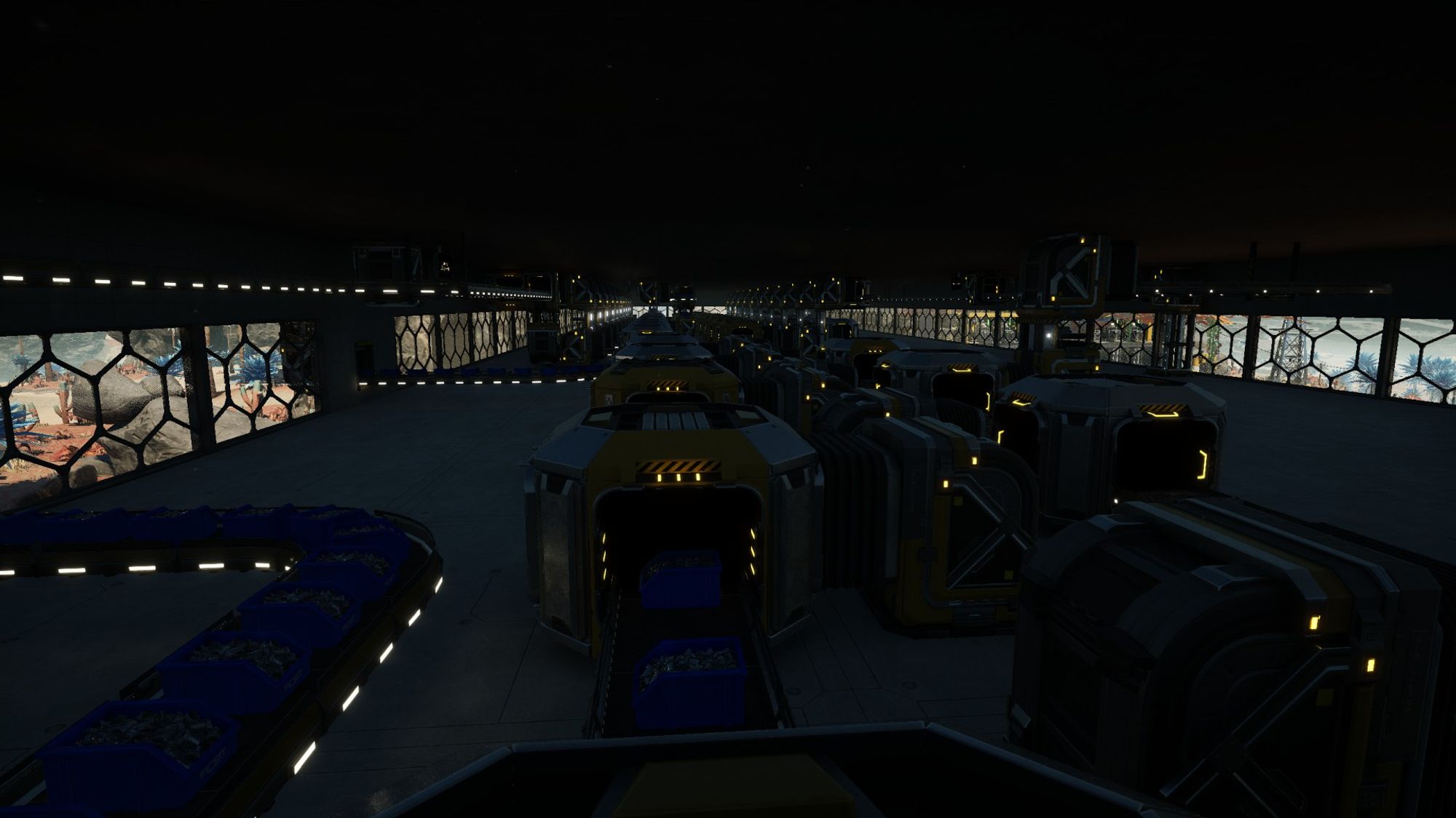 Satisfactory video game screenshot: In a dark factory floor, conveyor belts meet up with merger and splitter devices to move materials around.