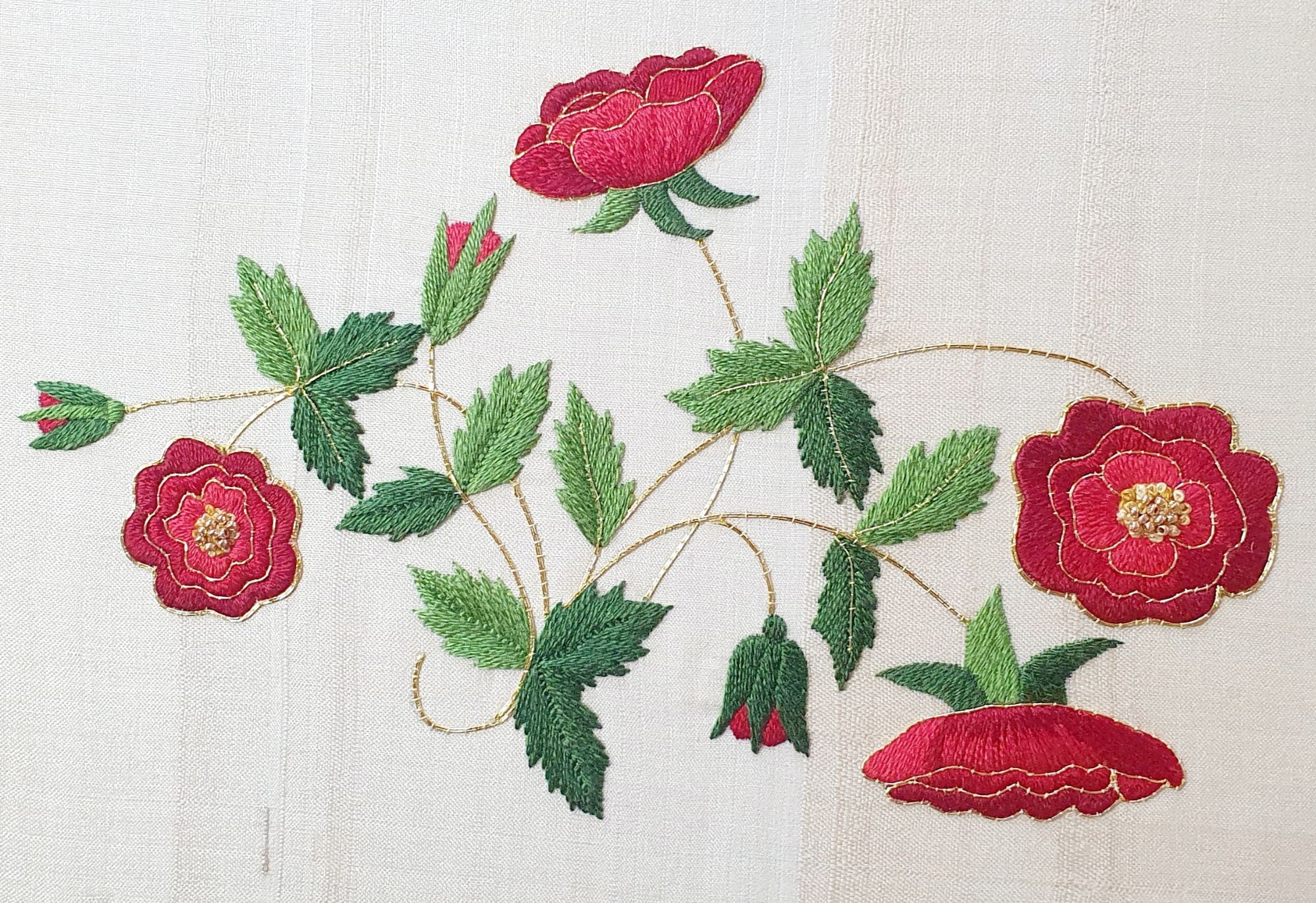 An embroidered cluster of red roses with green leaves, in silk and goldwork