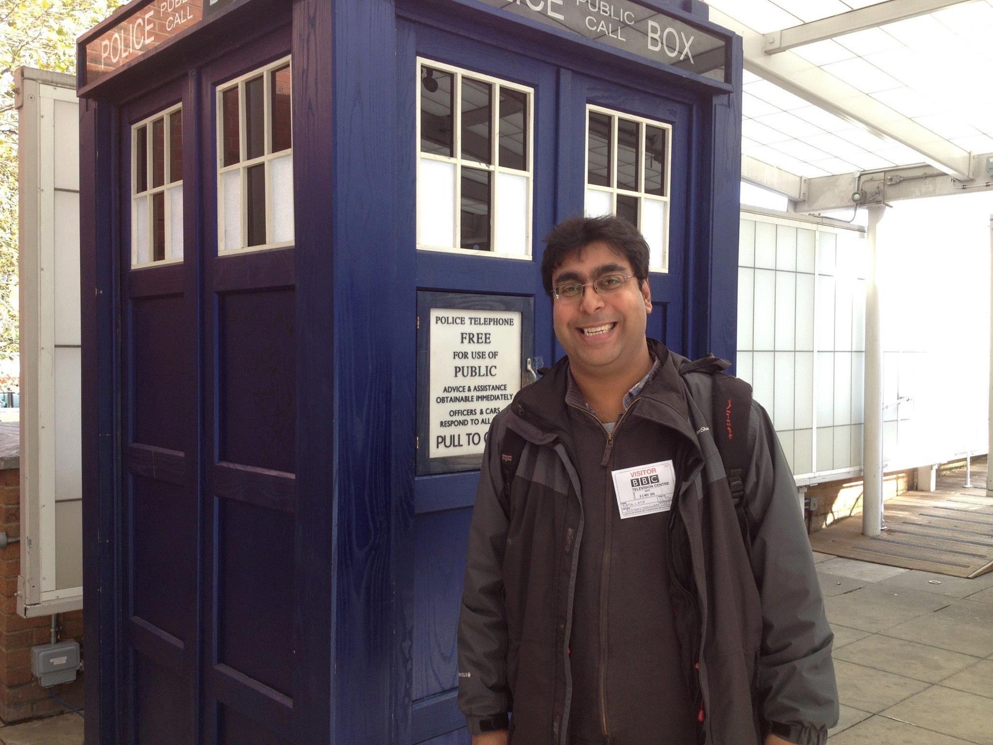 Myself, Kam Latif, standing in front of the TARDIS Blue Police Phone box outside BBC TV studios in 2012