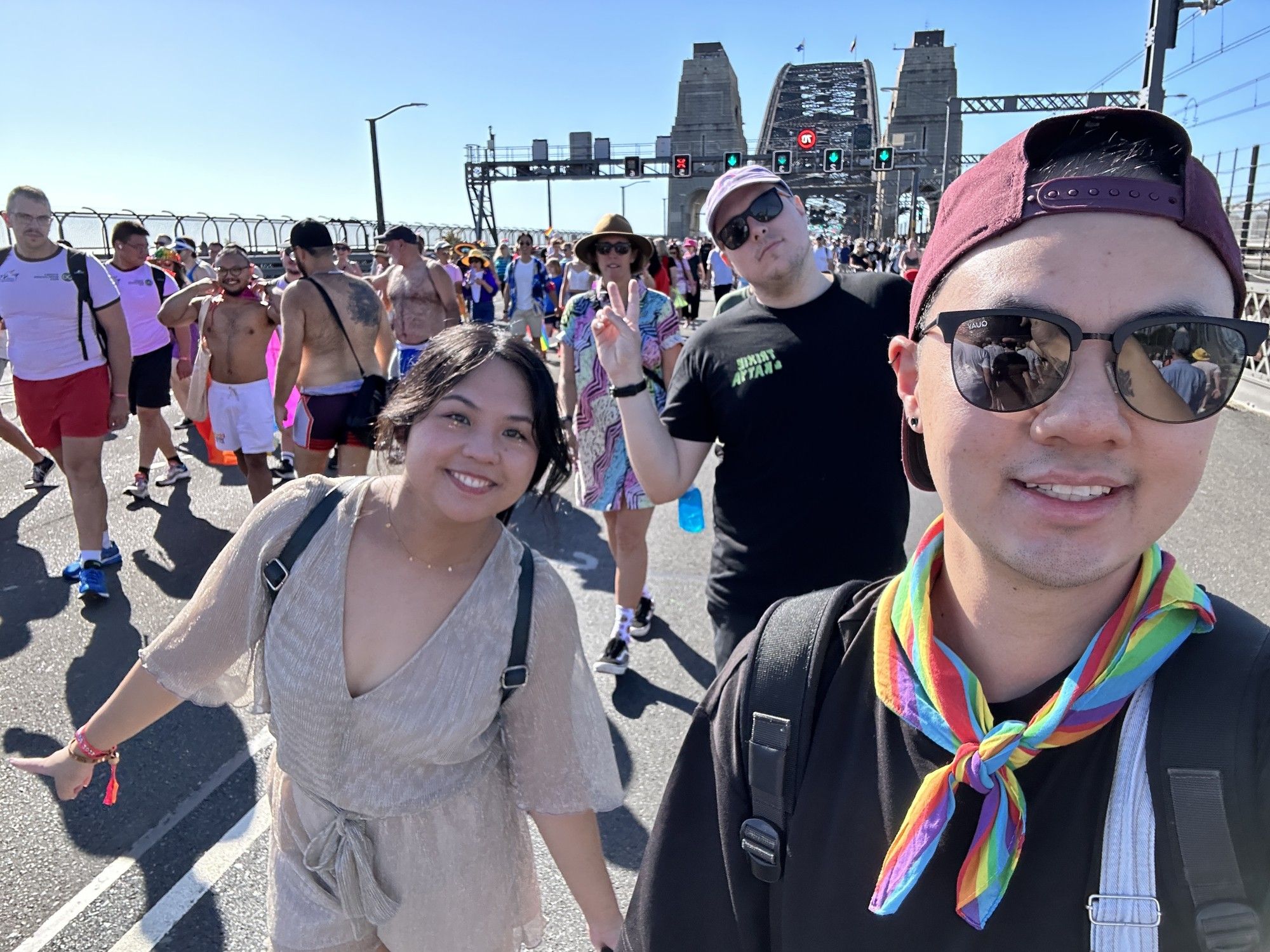 A group photo of Pup Alexx and his friends with the Sydney Harbor bridge in the background, walking in the Pride March event during World Pride 