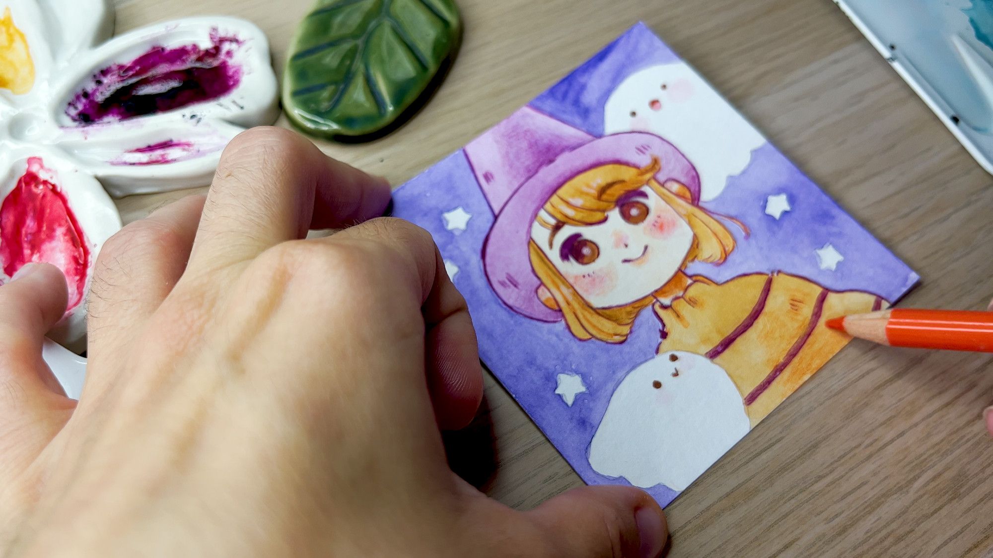 A photo of my hand drawing a little watercolor portrait!