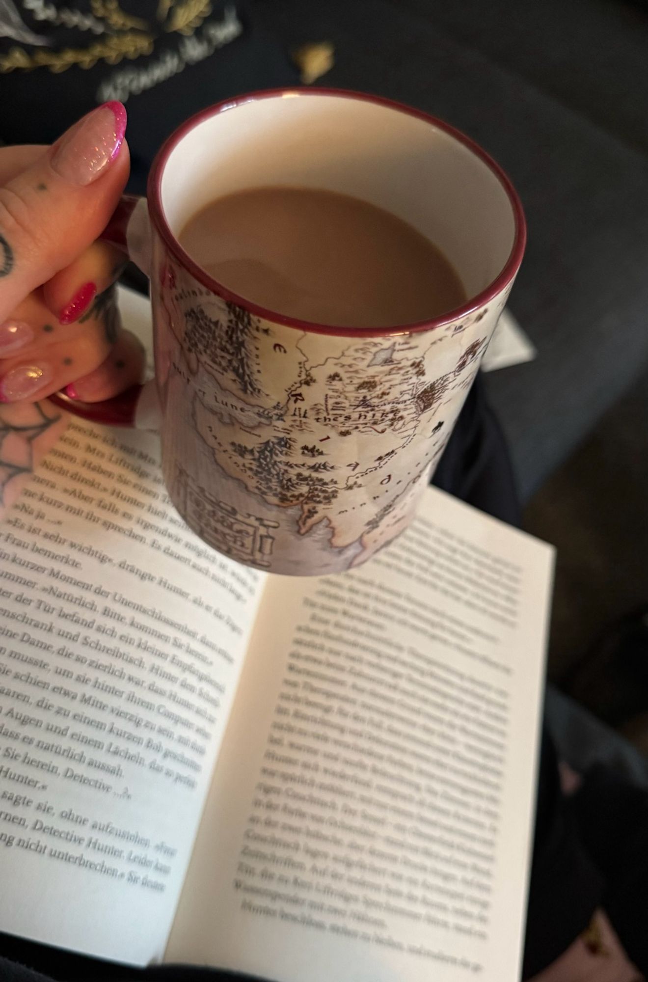 Auf meinem Schoß ein Buch und in meiner Hand eine Mittelerde Tasse mit Kakao