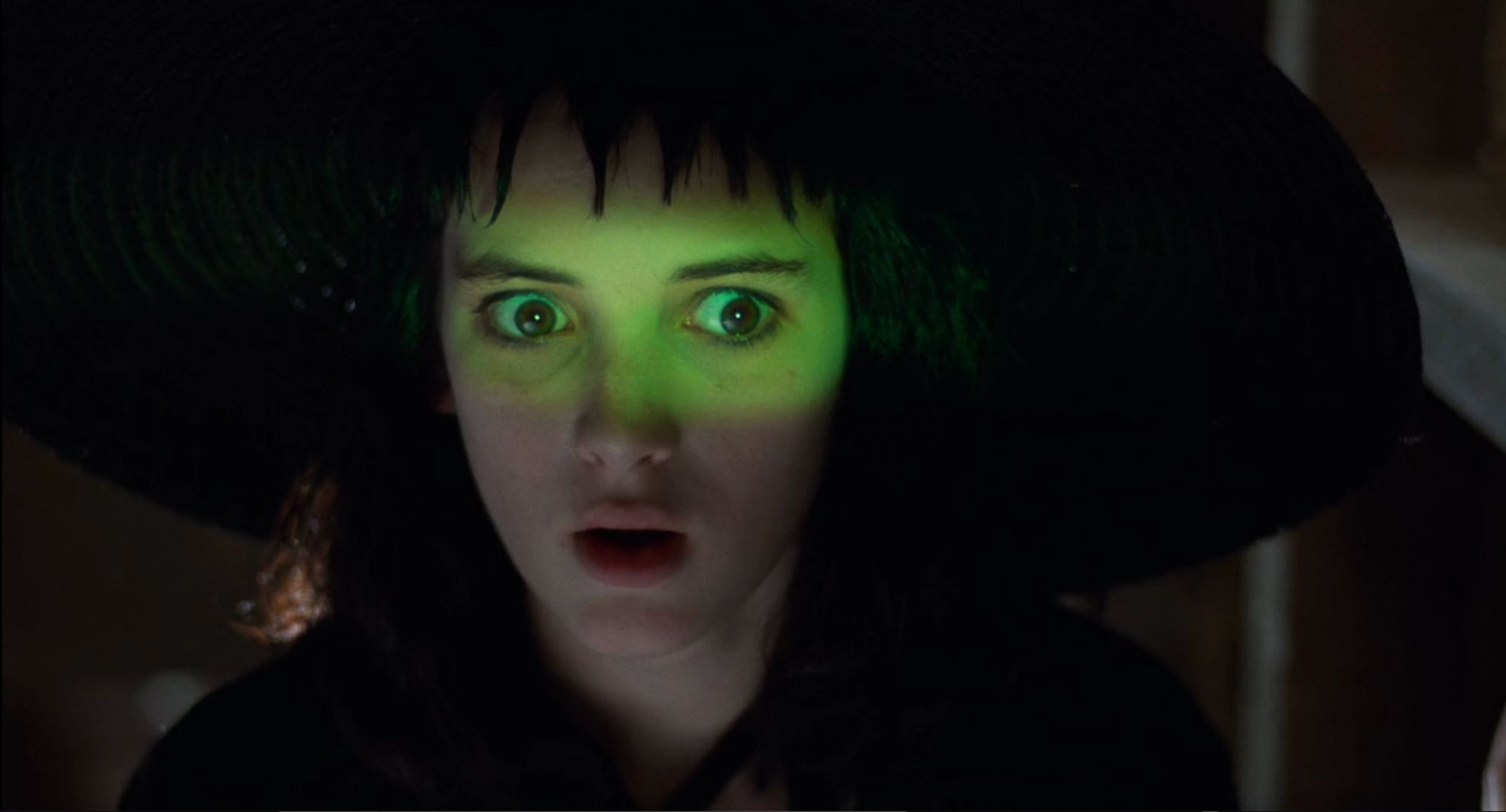 closeup of Winona Ryder/Lydia's face with green light over her eyes