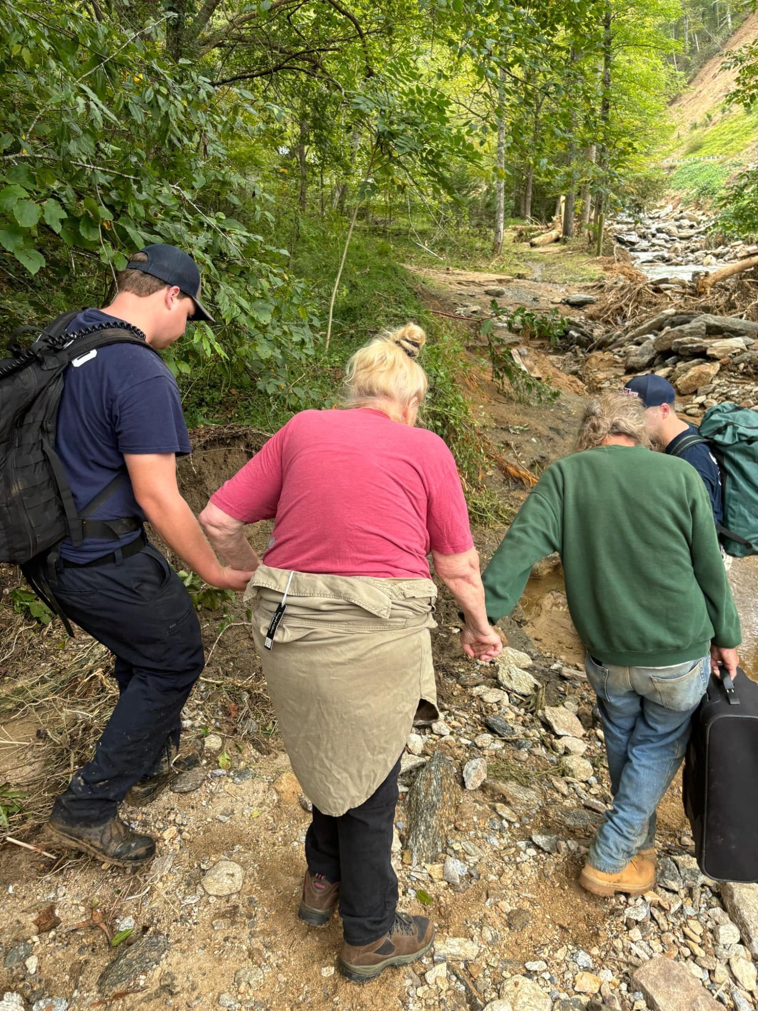 This is not my grandmother, who passed away earlier this year, but it could have been. Imagine being elderly, mountain poor, seeing your entire life destroyed before your eyes and having to be helped through wilderness with what's left of your life in one suitcase.

Search and rescuers helping an older woman who's clearly stooped and has faltering steps along a riverbank. Everyone's back is to the camera. One man is holding a suitcase.