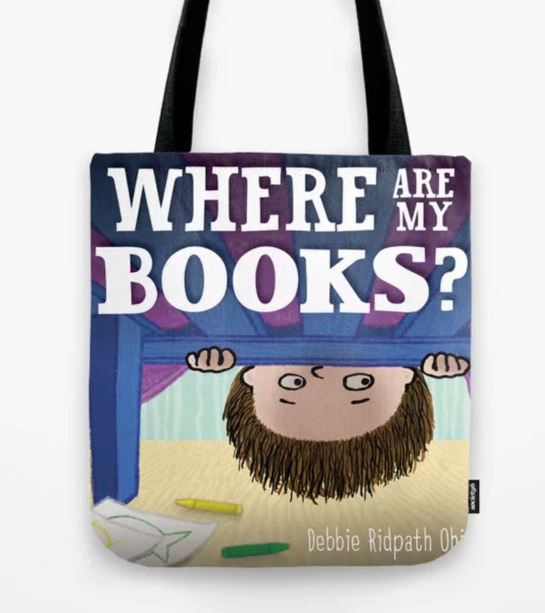 The image depicts a tote bag featuring a whimsical illustration. The illustration shows a child with a puzzled expression looking upside down from underneath what appears to be a piece of furniture, such as a bed. The child has short brown hair and is peeking out with hands grasping the edge of the bed. Scattered around the floor are a few crayons and a piece of paper with a drawing on it. The text on the bag reads, "WHERE ARE MY BOOKS?" in large, bold white letters, with the name "Debbie Ridpath Ohi" in smaller text at the bottom.