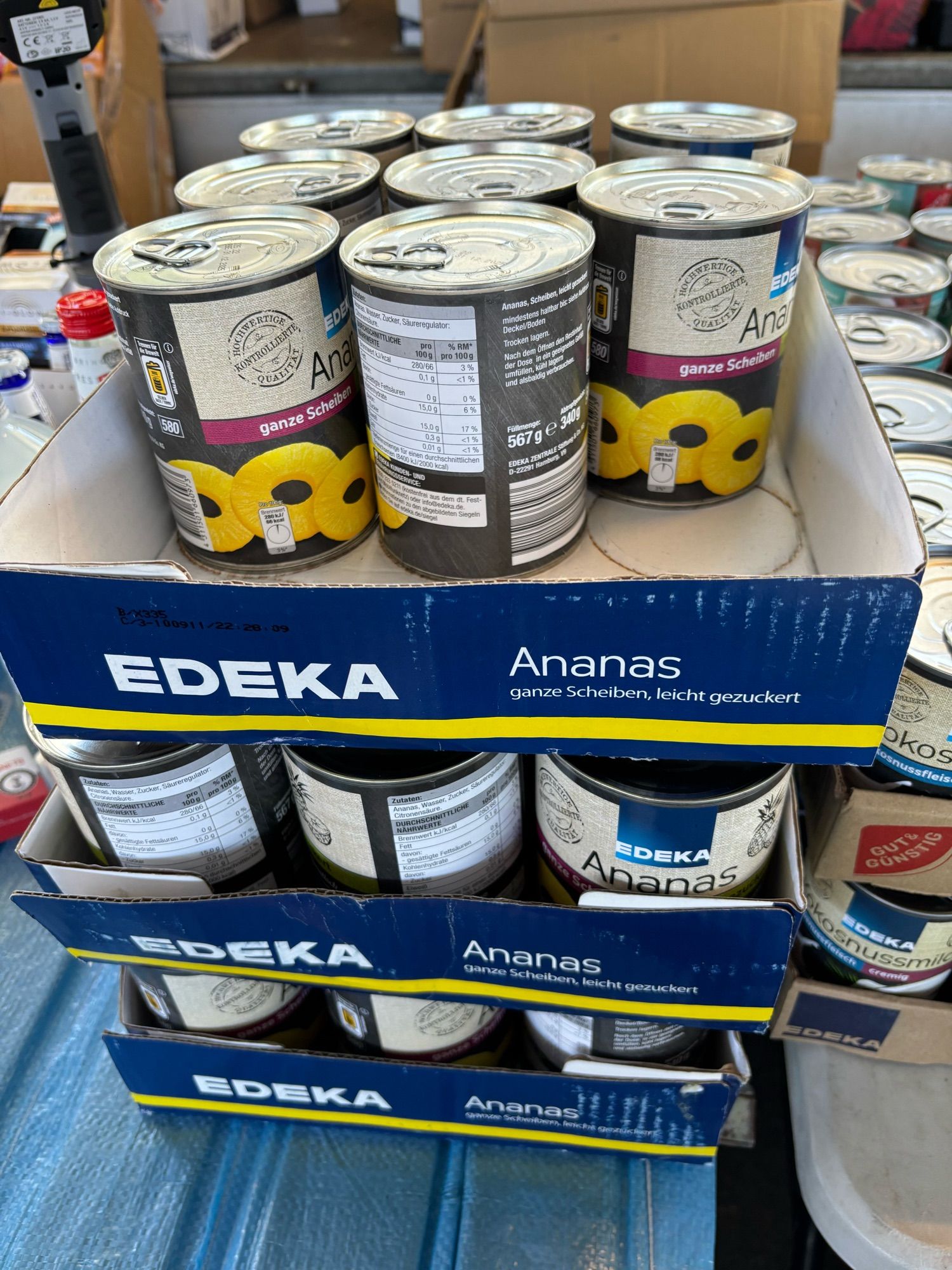 Mehrere EDEKA-Paletten voller Dosenananasringe.