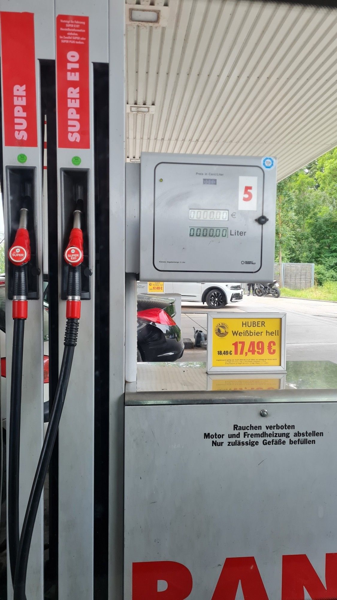 Tankstelle: An der Zapfsäule steht ein Werbeschild für Bier der Marke Huber direkt neben den Zapfhähnen.