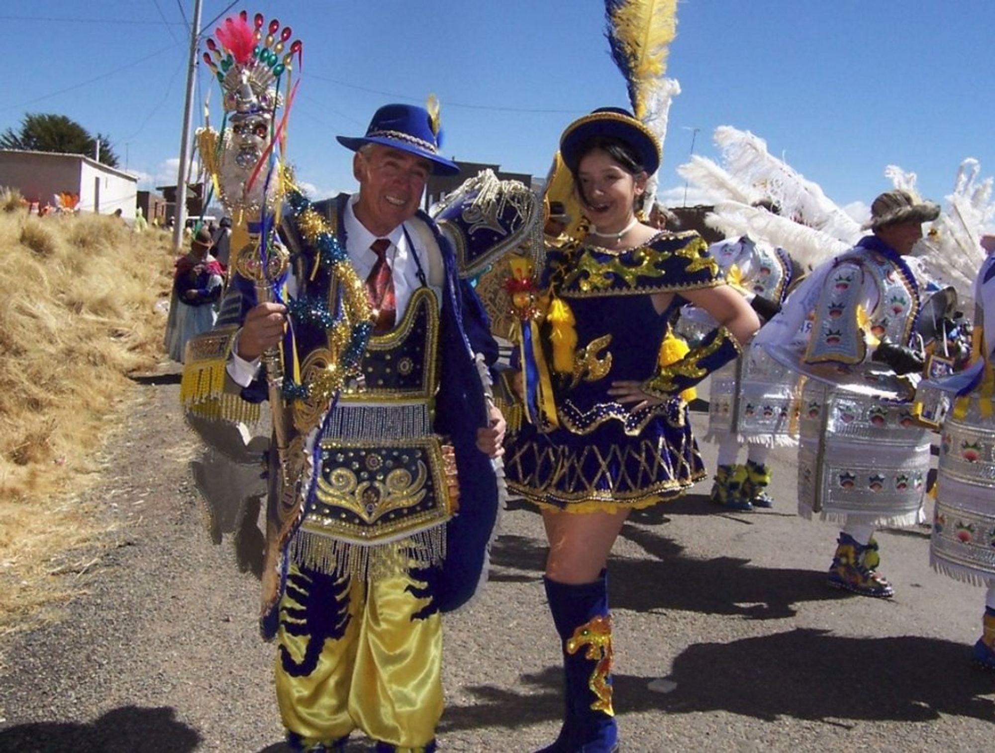 Photo of Aida (right) in a Bolivian folkloric costume for the Morenada dance. Royal blue velvet off-shoulder sleeveless top with pleated and ruffled mini skirt. Gold and yellow sequins and embroidery. Knee-high boots with golden sequins. Bolero hat with tall blue and yellow feathers.