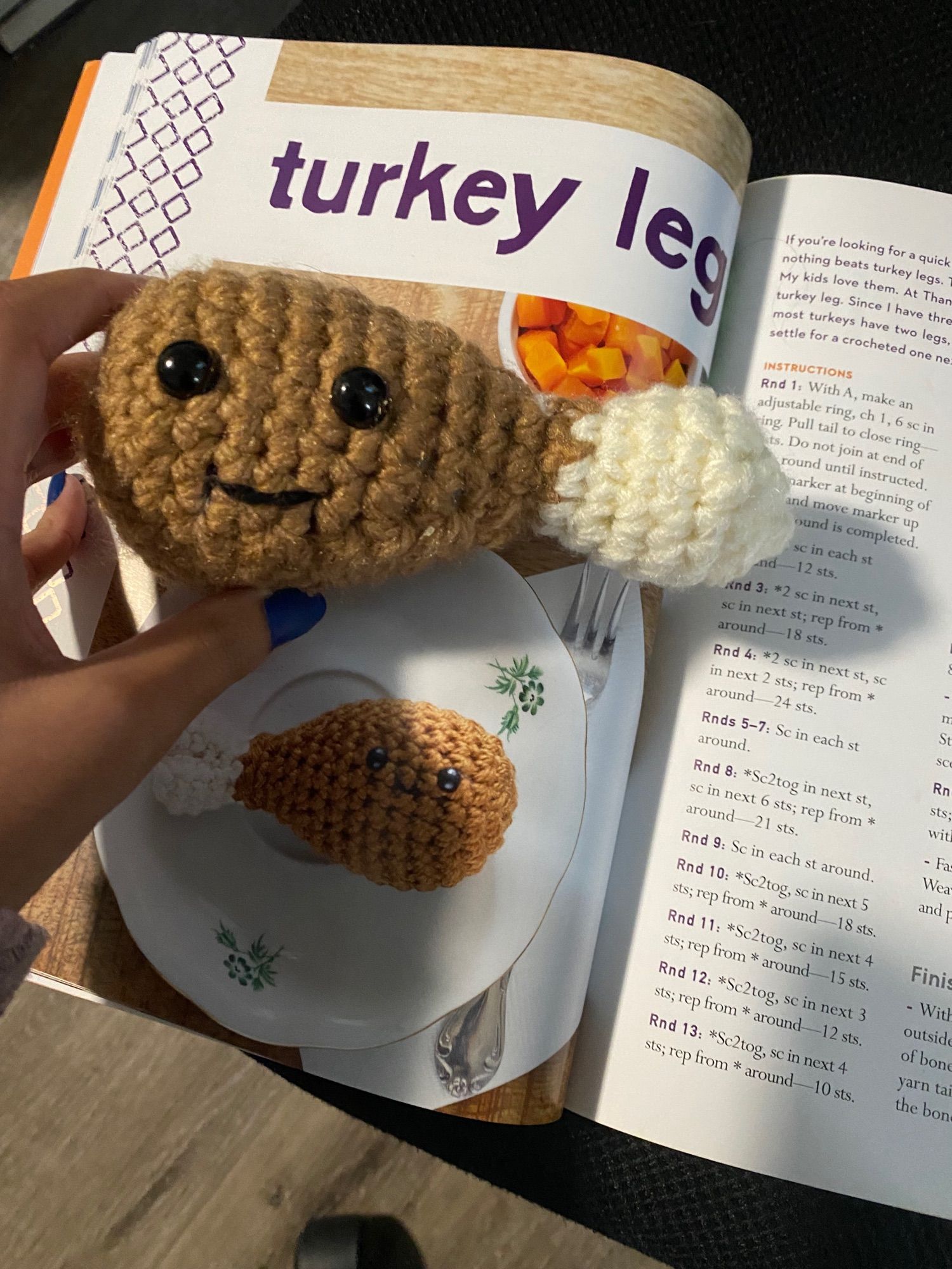 Photo of my hand holding Octavio the Turkey Leg on top of the book "amugurume eats"