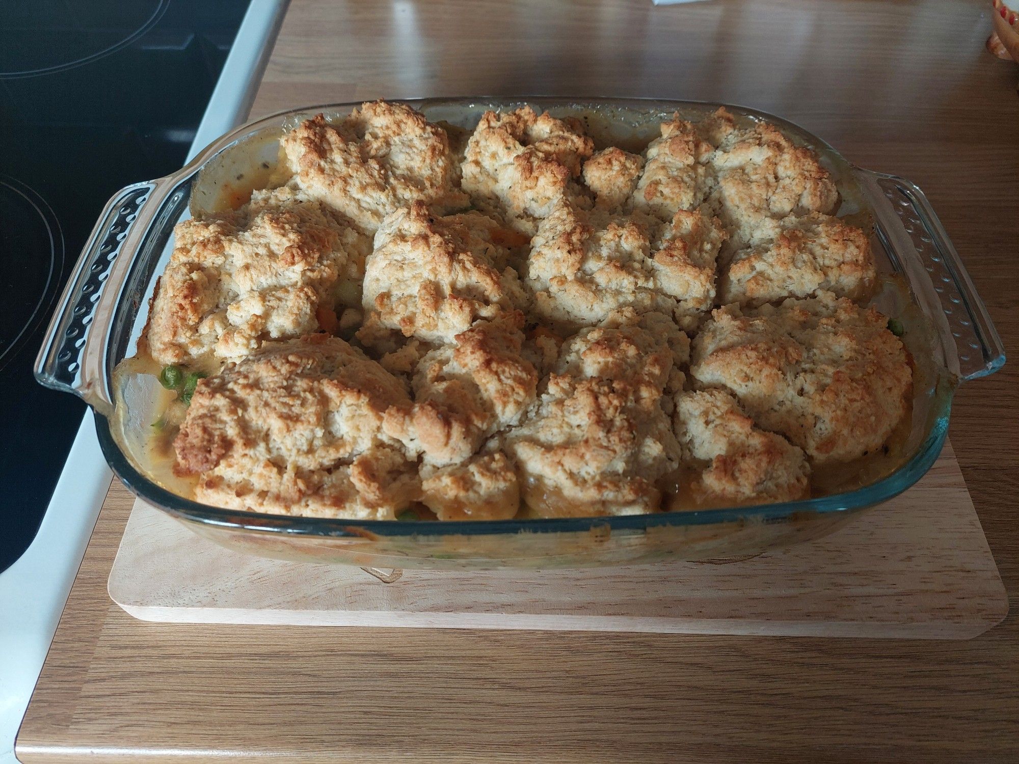 Chicken and leek savoury cobbler in a glass baking dish sittin on a wooden board