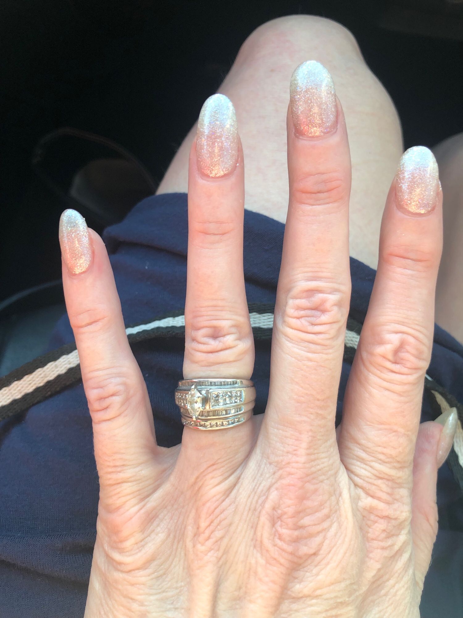 Jenny’s left hand with pink sparkly sculptured nails and wedding ring