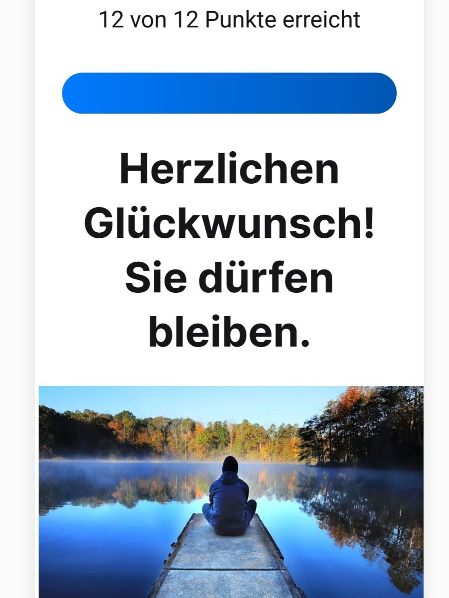 Mensch sitzt mit dem Rücken zum Betrachter auf einem Steg mit Blick auf einen See. Rechts und ganz hinten stehen Bäume die sich im See spiegeln!