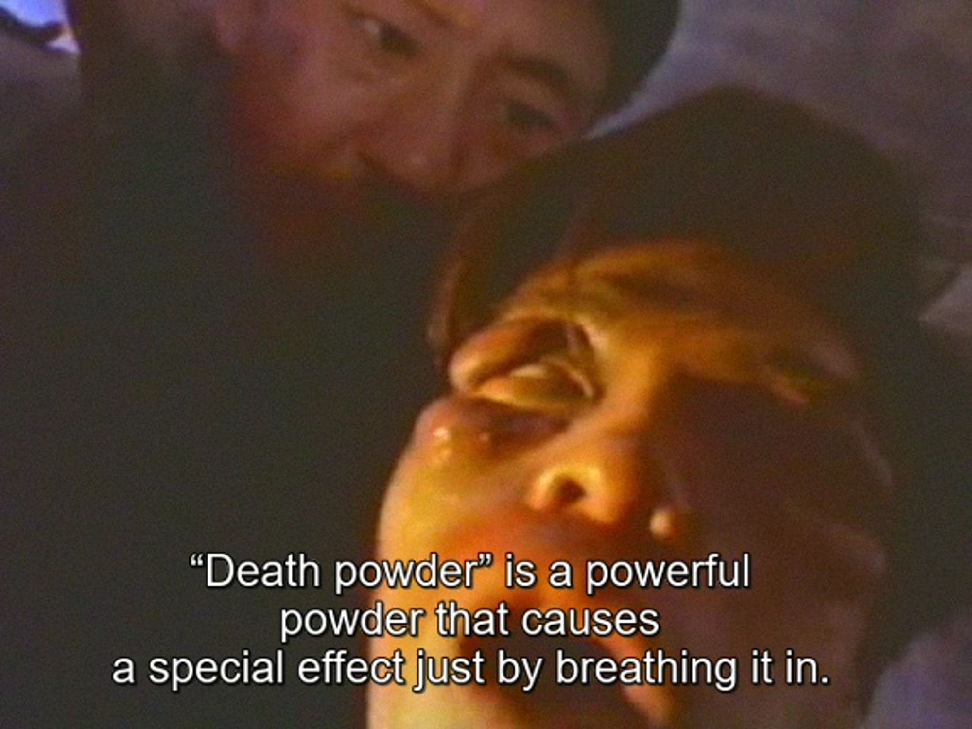 Still from Death Powder (1986). A man appears to be turning into a zombie while another guy stands behind him, explaining what's happening. Caption: "Death powder" is a powerful powder that causes a special effect just by breathing it in.