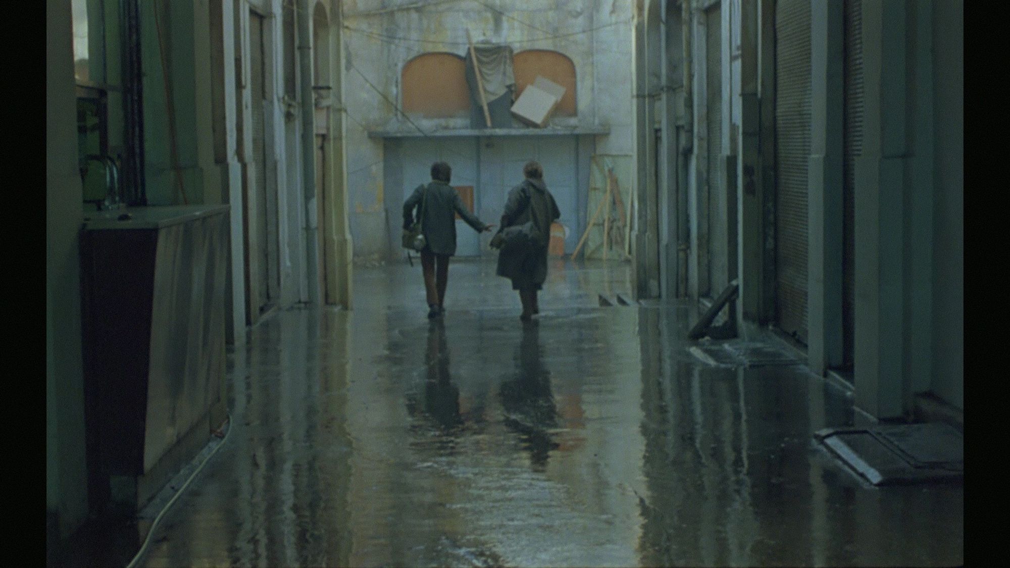 Two wet post-apocalyptic survivors explore a rainy industrial tunnel in post-apocalyptic Athens