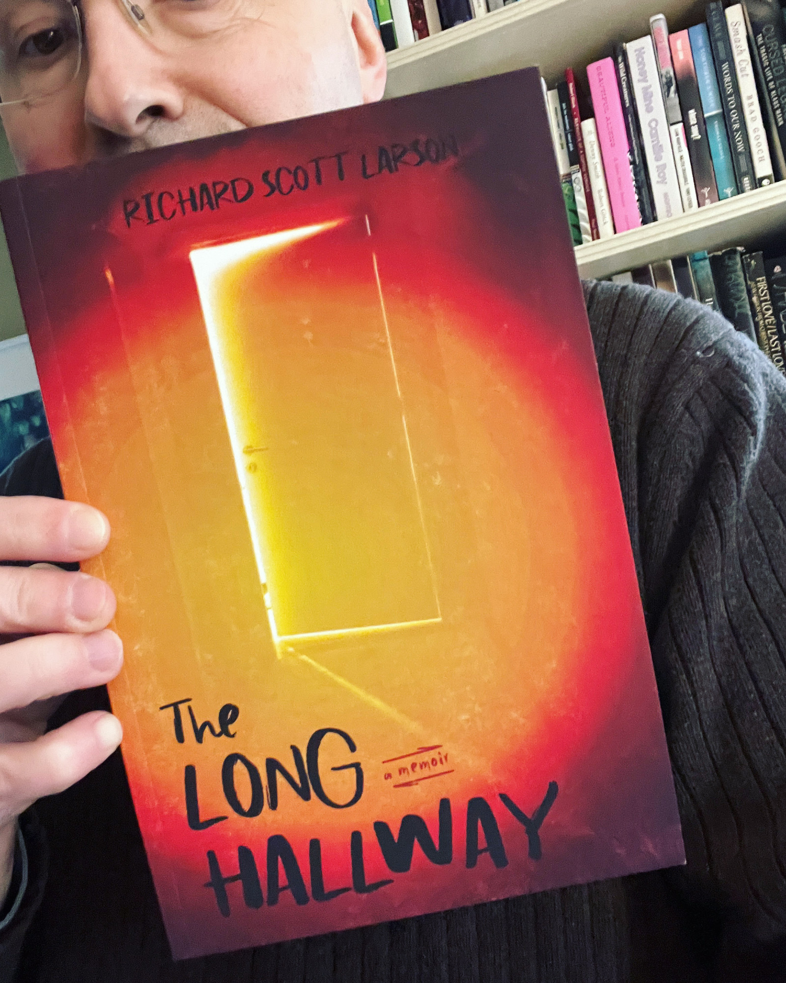 person holding a copy of The Long Hallway by Richard Scott Larson