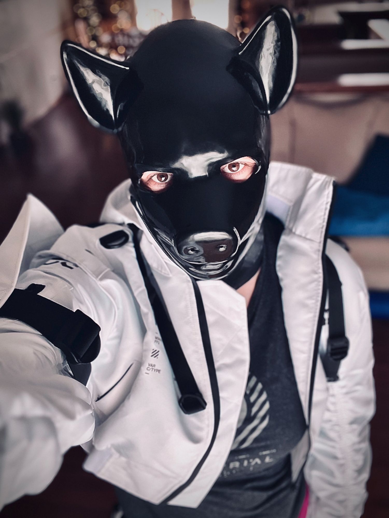 A selfie of me wearing my black rubber pig hood, a white techwear jacket, and a dark grey tank top underneath.