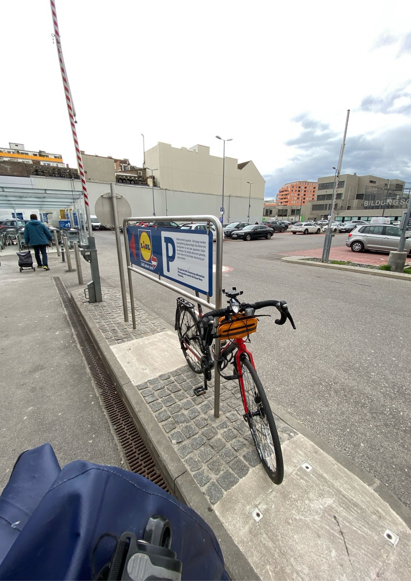 Ebenfalls ein Foto von einem Fahrrad an dieser Lidl Filiale. Im Hintergrund ist ein sehr großer Auto Parkplatz der Lidl Filiale zu sehen mit über 70 Stellplätzen.