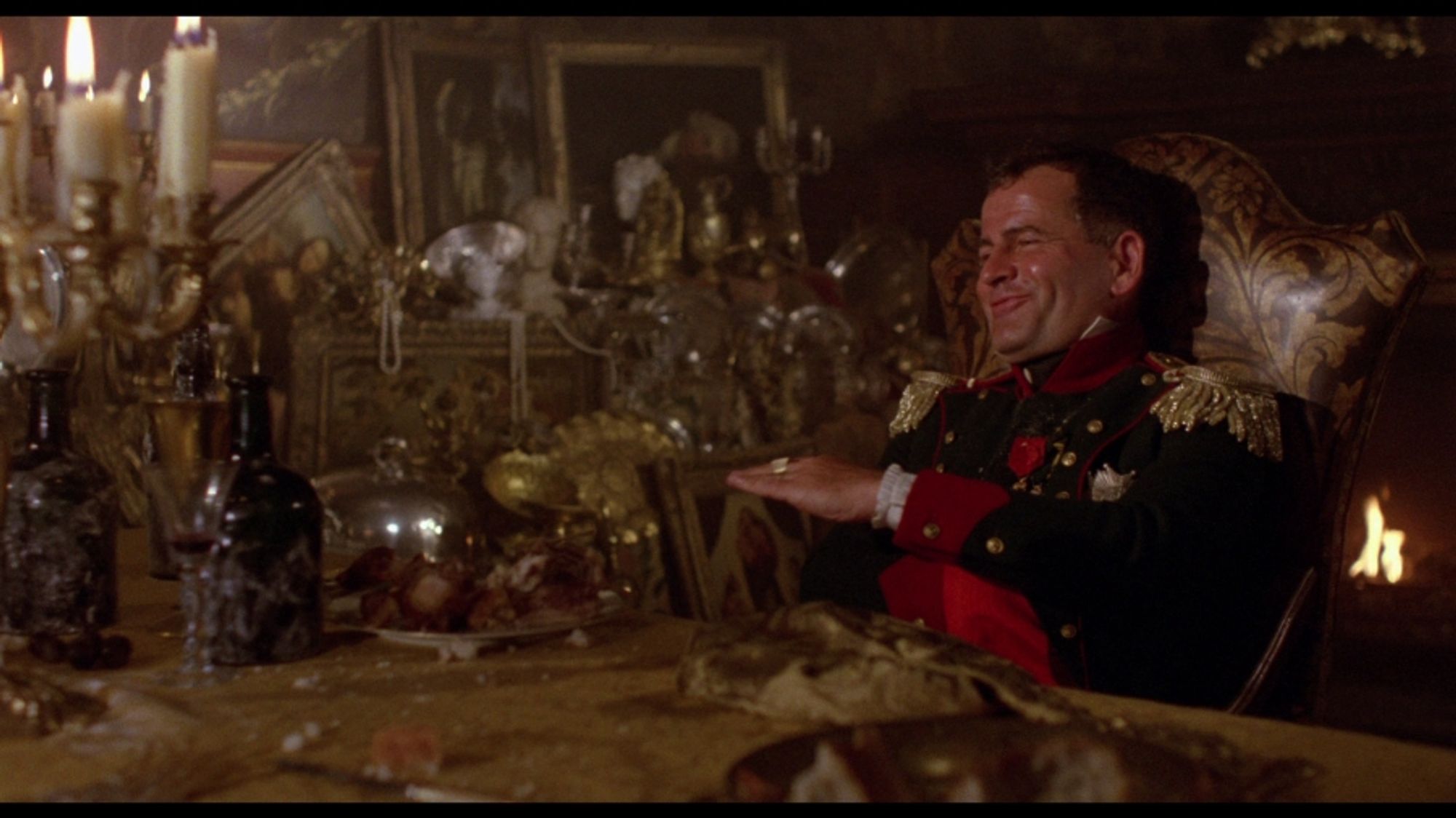 Ian Holm as Napoleon in Time Bandits, sitting at his luxurious dining table, surrounded by the spoils of war, red faced and full of himself 