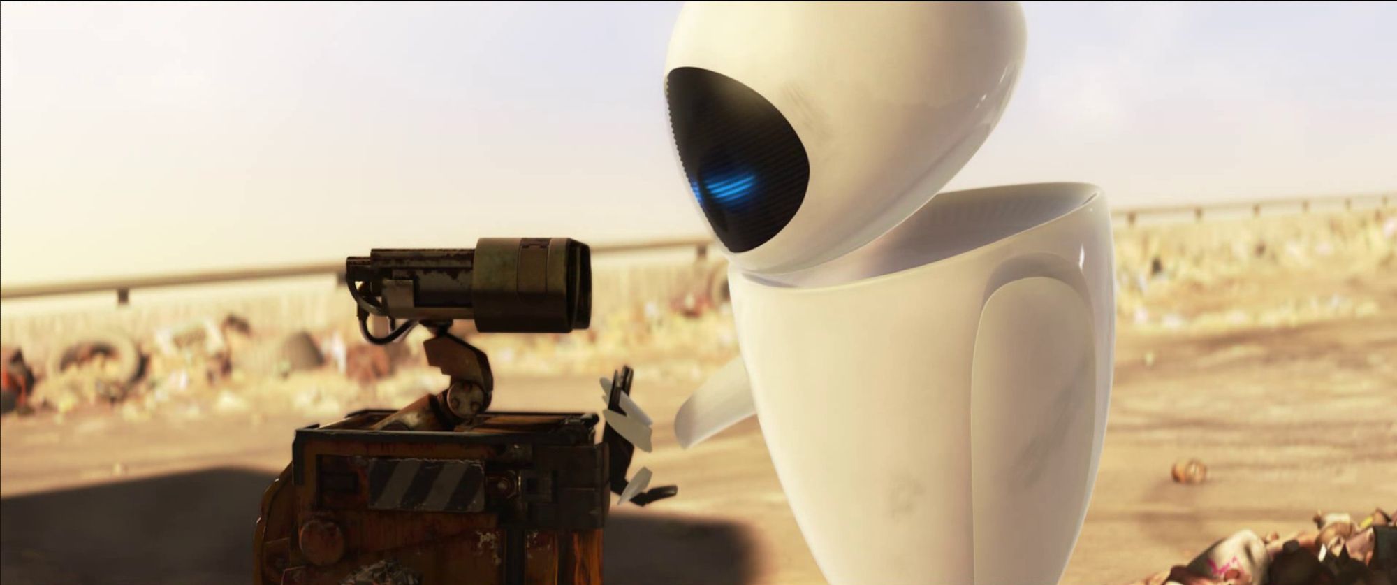 Wall-E, a small cuboid junk robot, holds hands with EVE, a sleek, futuristic robot, in a wasteland that used to be Earth.